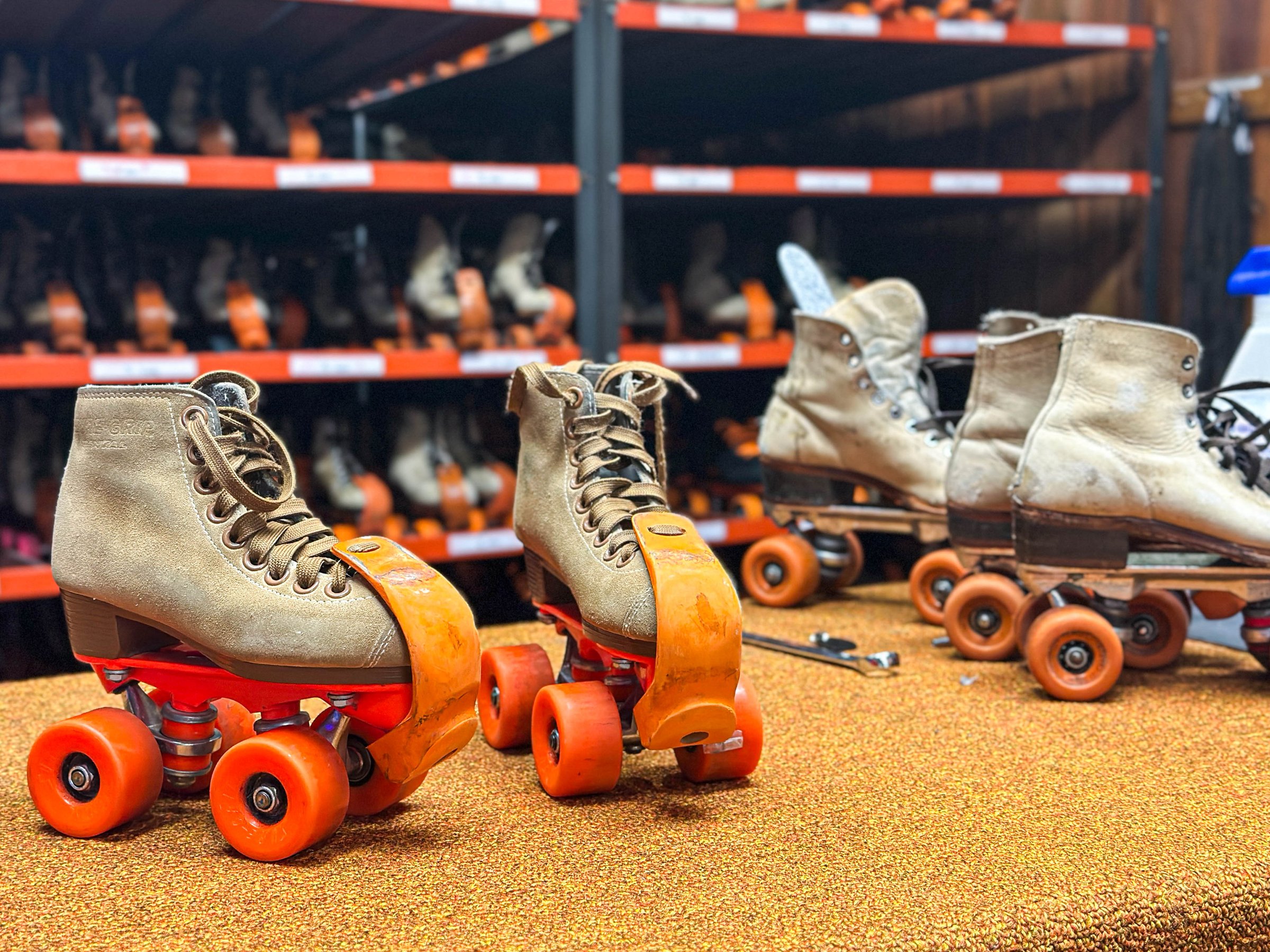 Vintage quad roller skates with bright orange wheels setting inthe return drop off at a roller skating rink. A nostalgic scene with a retro vibe.  perfect for themes of fun, recreation, and 80s–90s throwback culture.