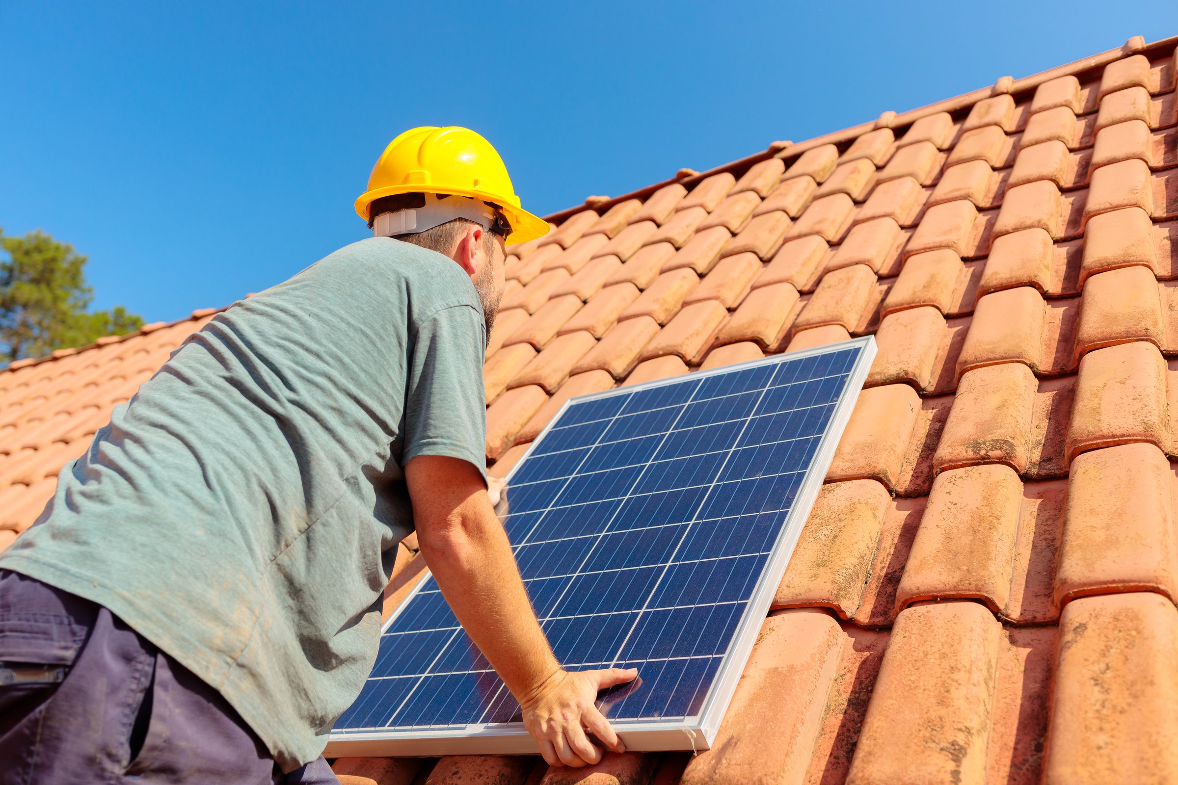 Technician installing a solar panel on a house roof, showcasing renewable energy solutions and sustainable living. Ideal for companies promoting clean energy and solar power installations