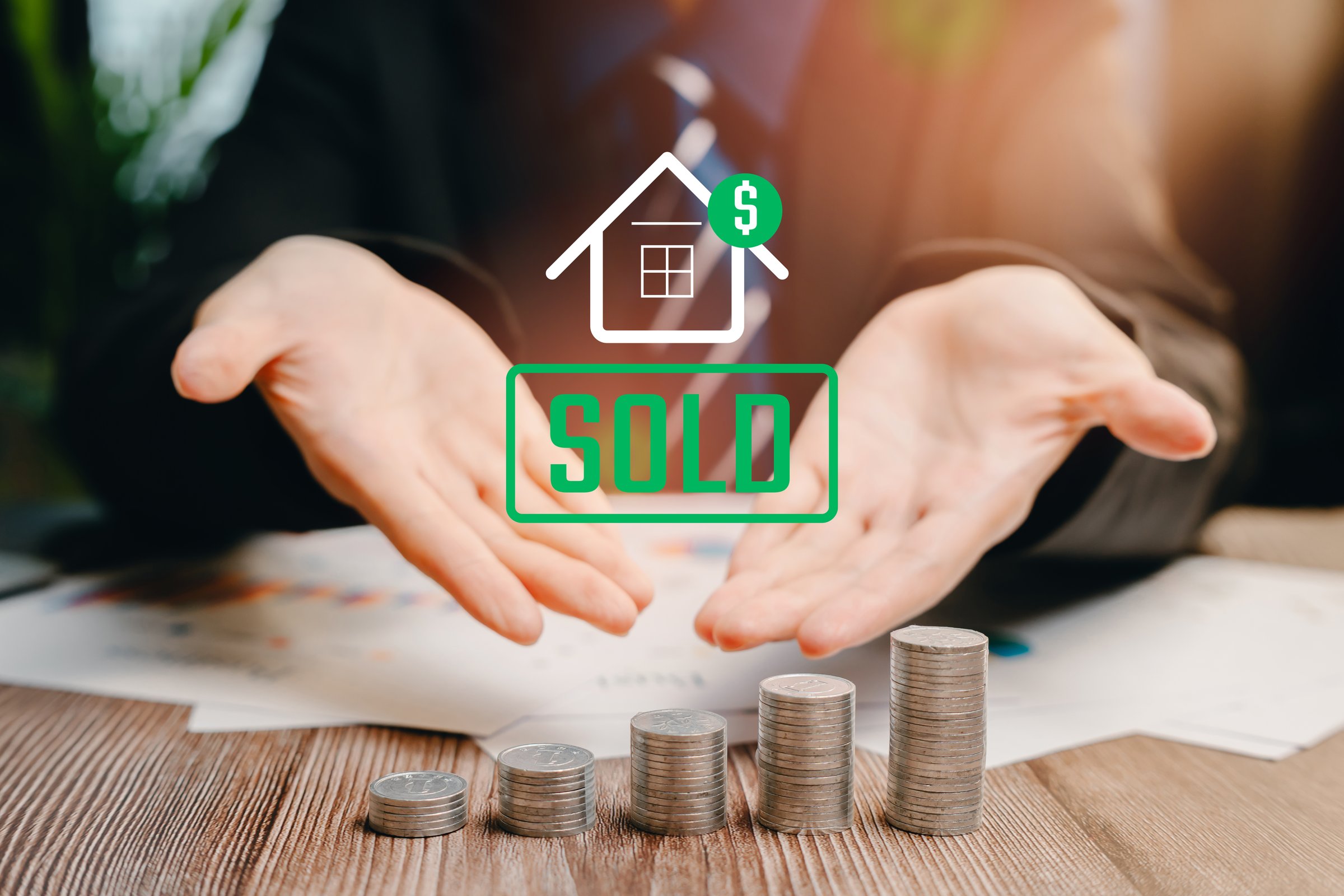 Sold House Concept. Businessman Presenting Sold House Concept with Stacked Coins and Financial Symbols for Real Estate Success.