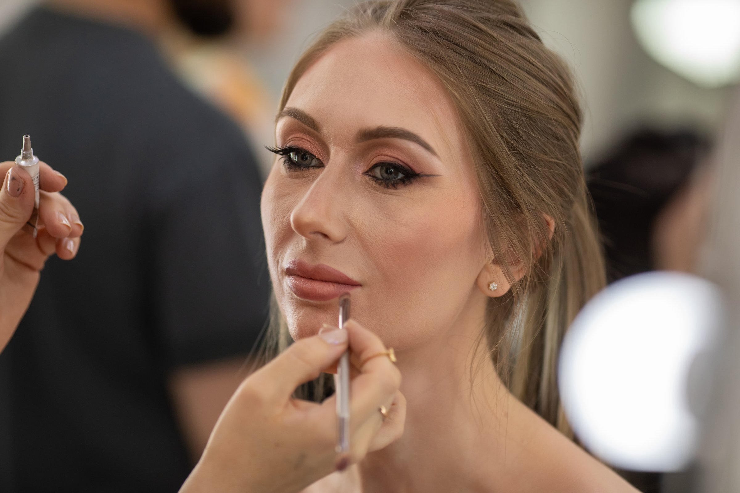 Professional Make-up artist doing makeup for smiling woman. Beauty salon.