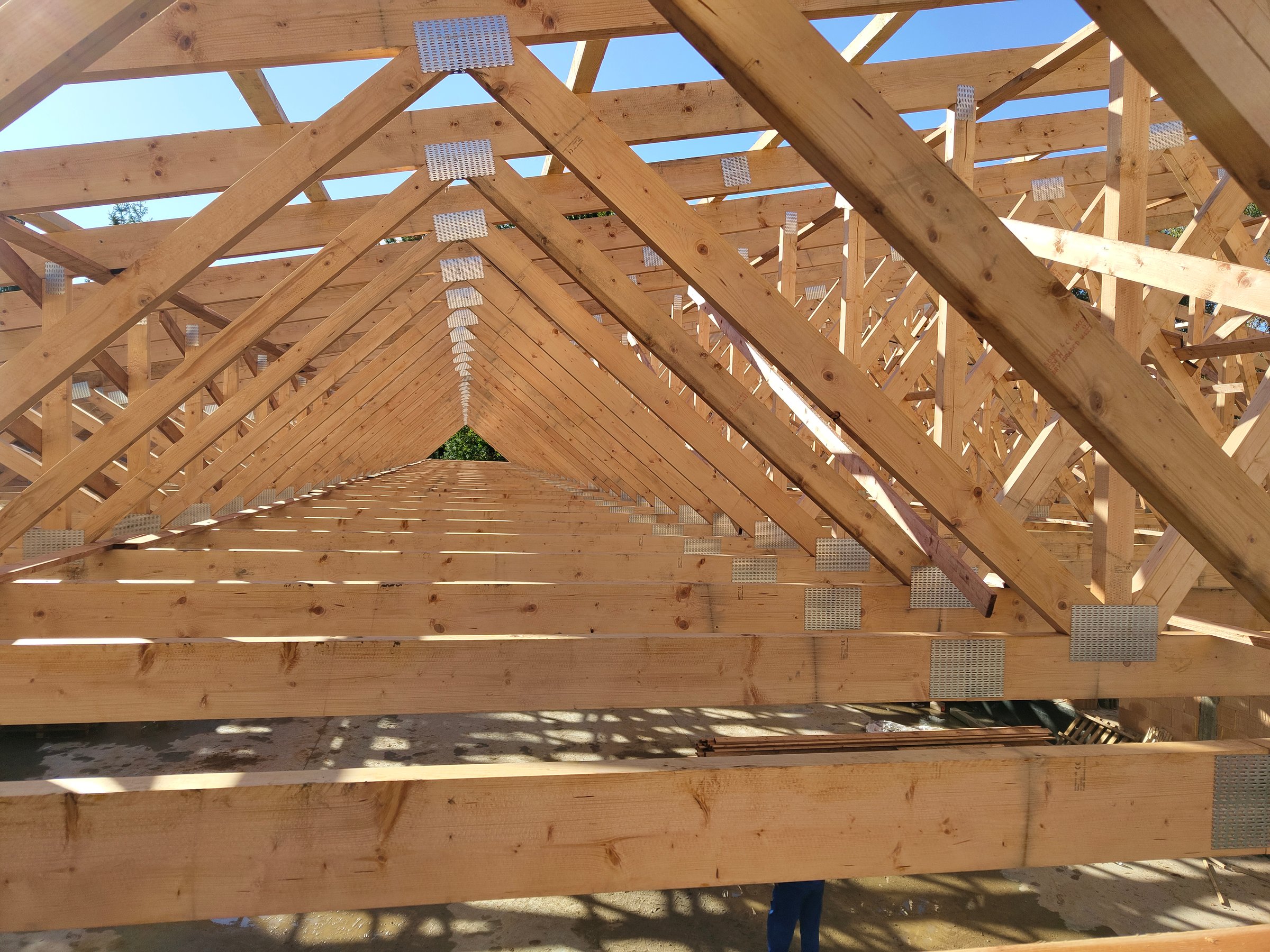 Long row of angled wooden trusses forming a structural frame, emphasizing the orderly layout under bright daylight.