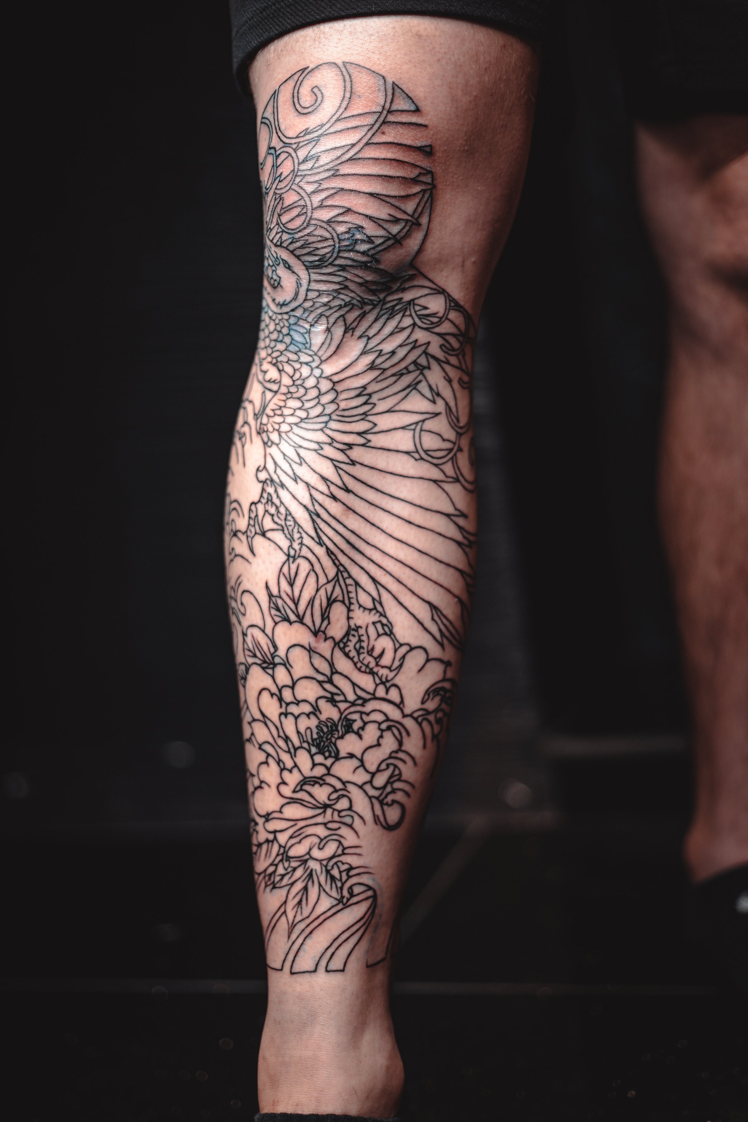 Man with cool tattoos on black background, closeup. Leg