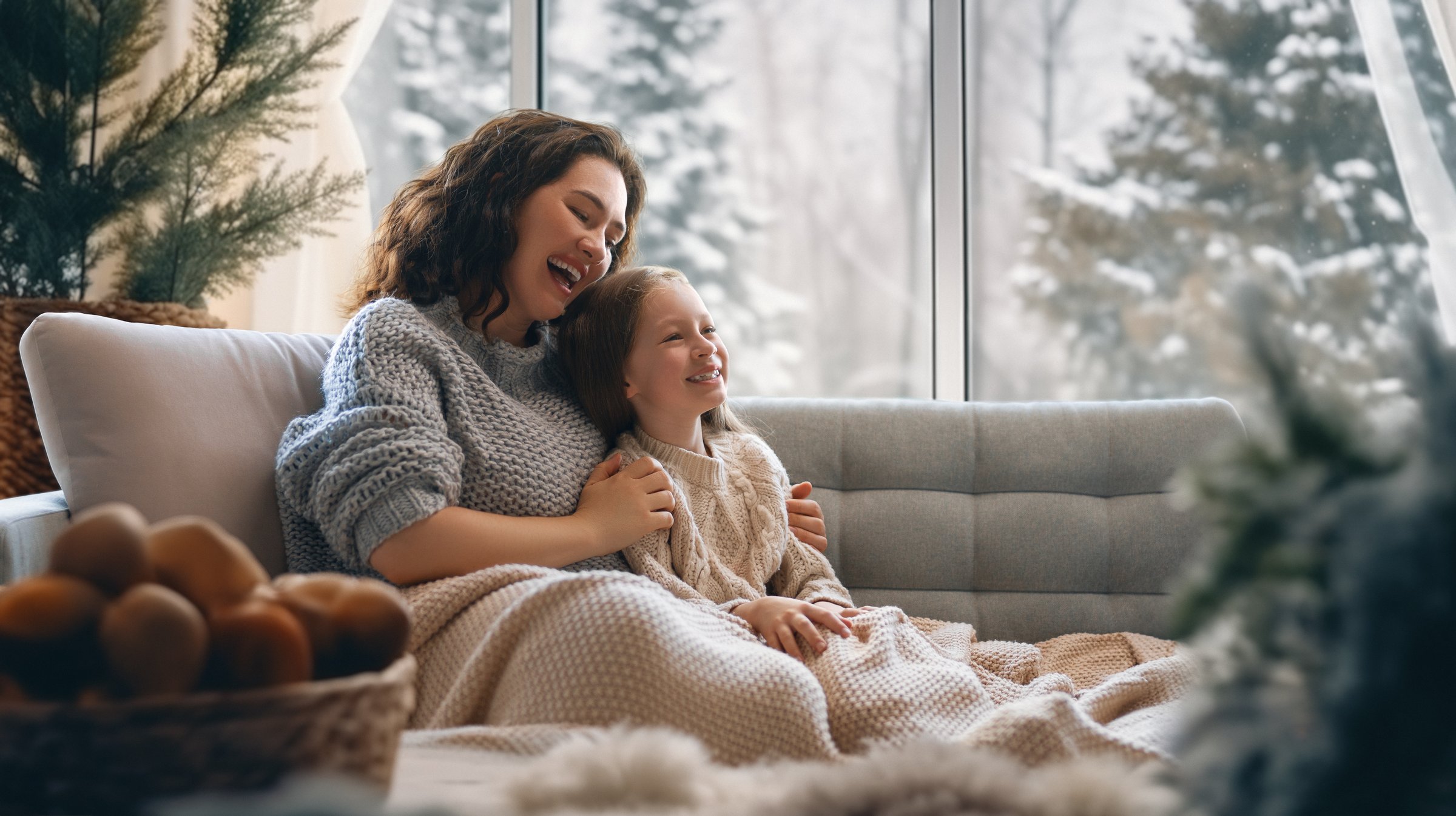 Happy loving family. Mother and daughter are hugging and enjoying winter nature in the  window.