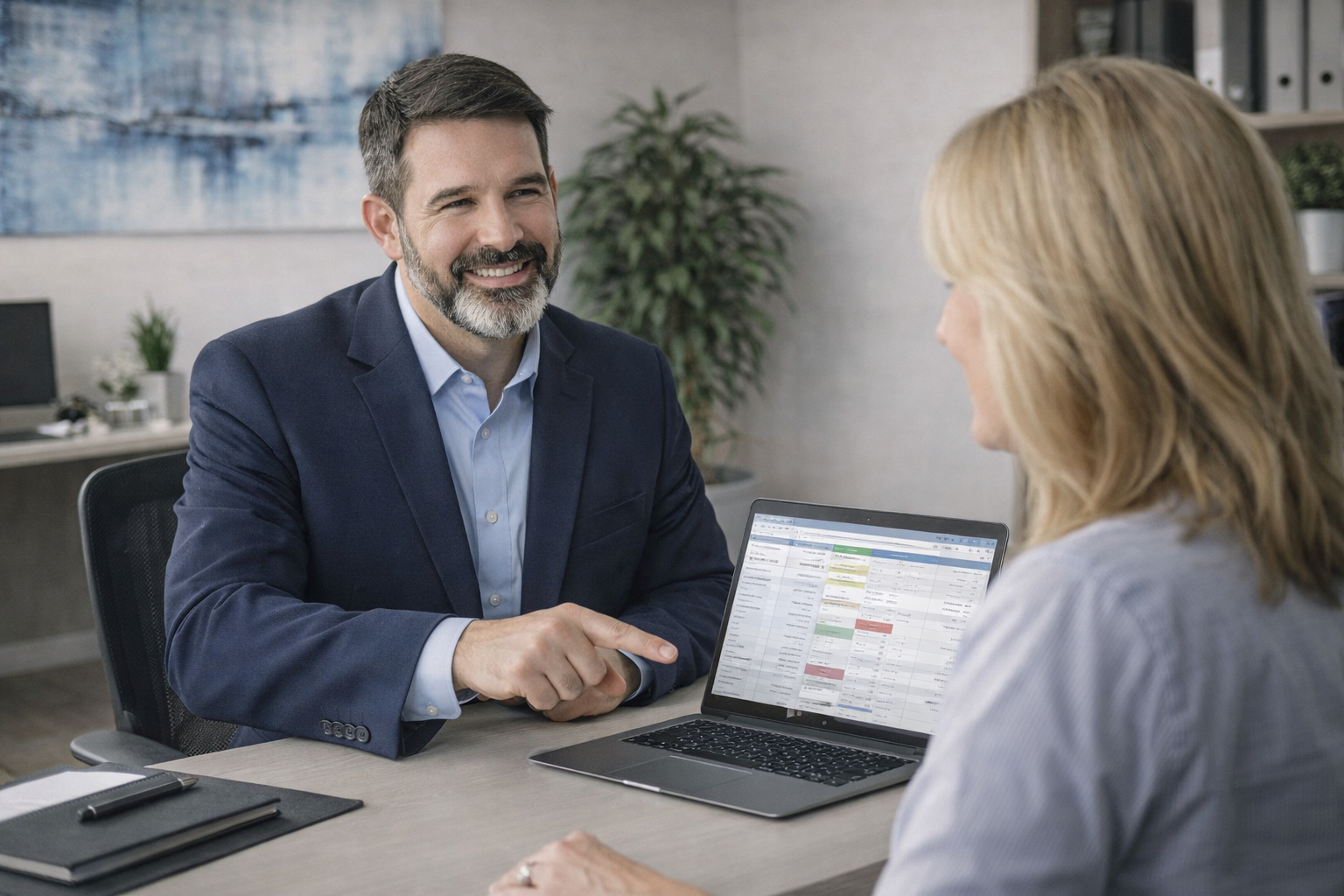 Suit Ron teaching Customer at desk with laptop