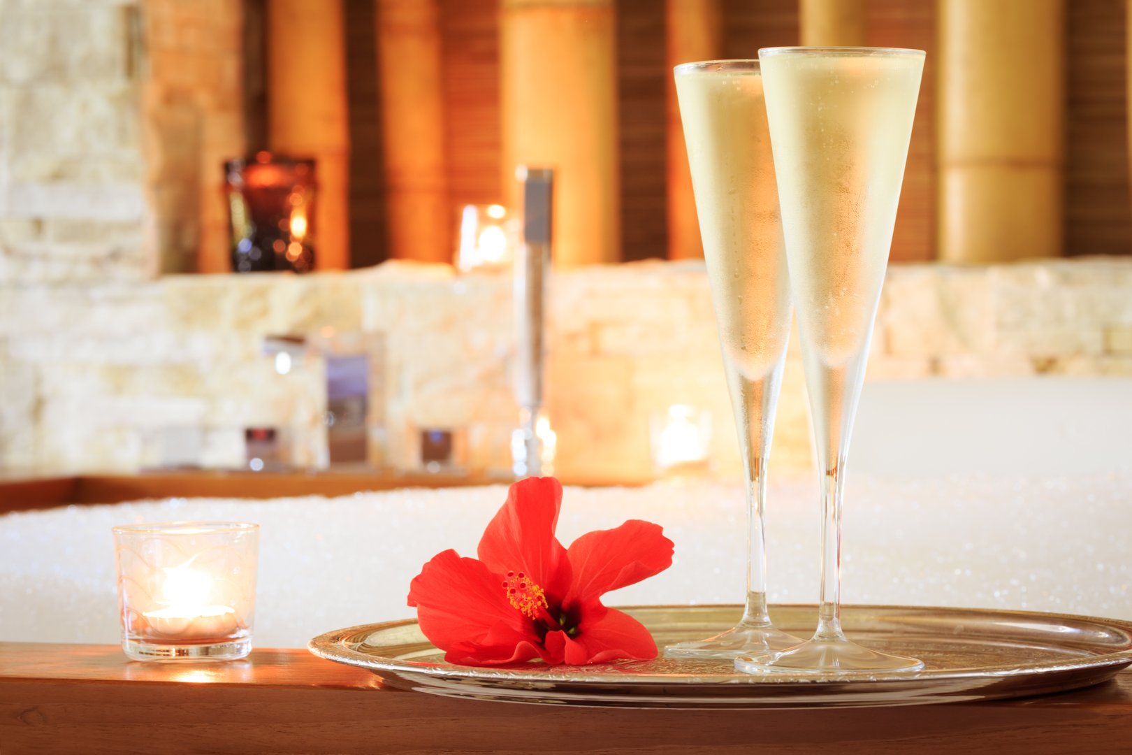 Two glasses of champagne with candle and red flower near hot tub. Valentines background. Romance concept. Horizontal