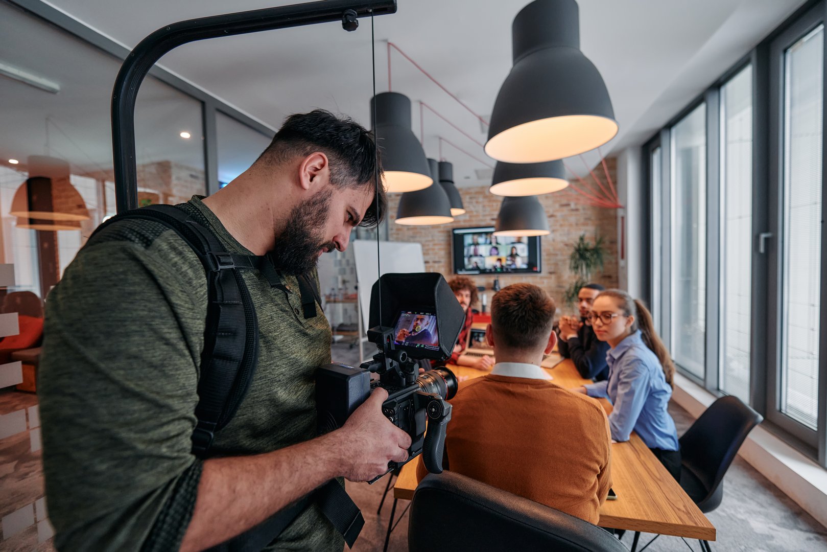 A videographer captures the essence of a business meeting in a modern office, skillfully documenting corporate dynamics and collaboration.
