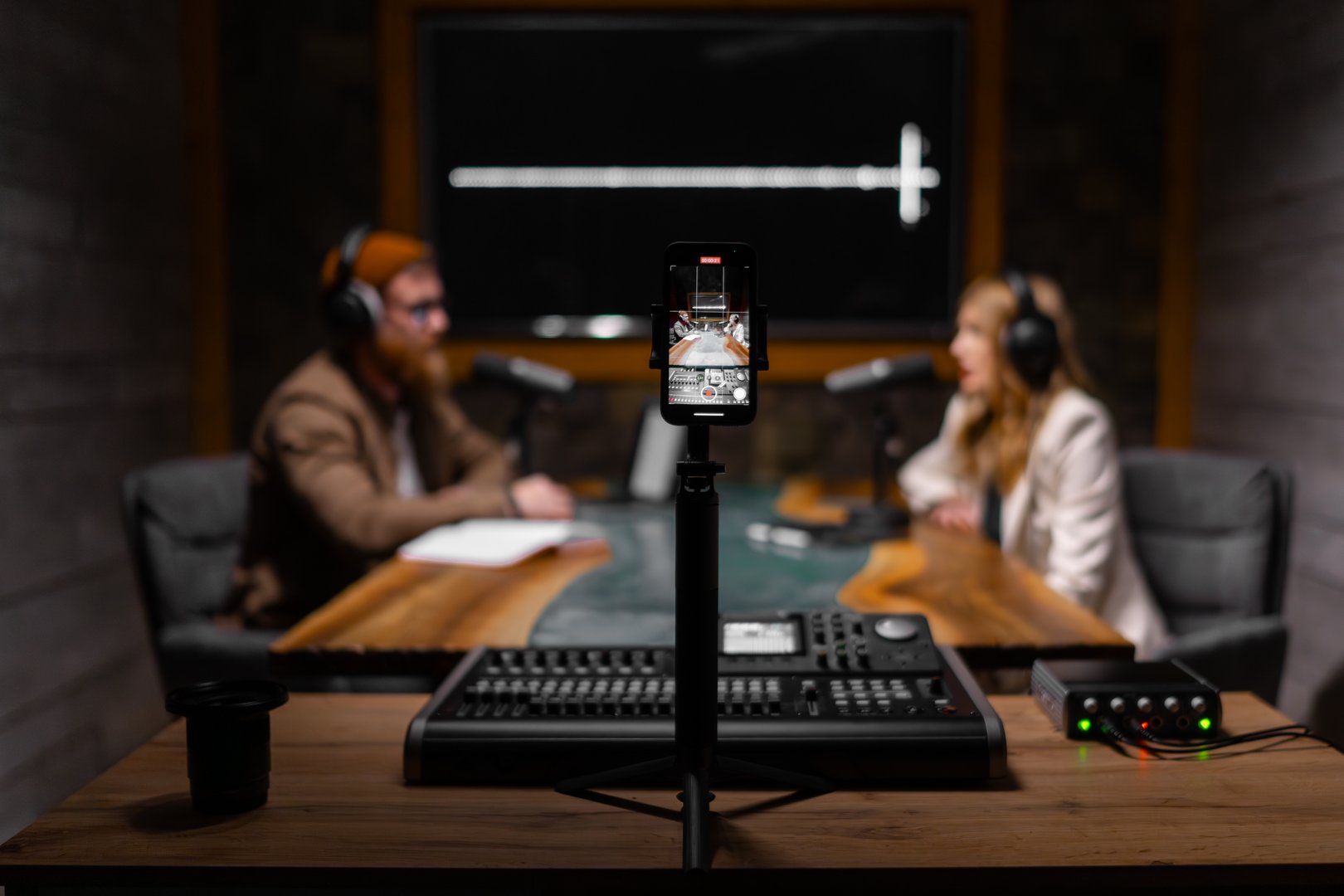 Two hosts engage in a discussion during a podcast recording in a well-equipped, modern studio.