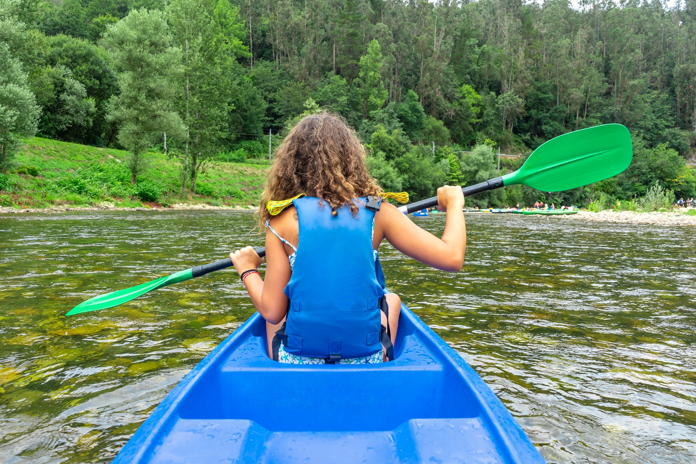 Rear view of a girl paddling in a kayak on the Sella river descent in Asturias, Spain. Active tourism activities. Rural tourism.
