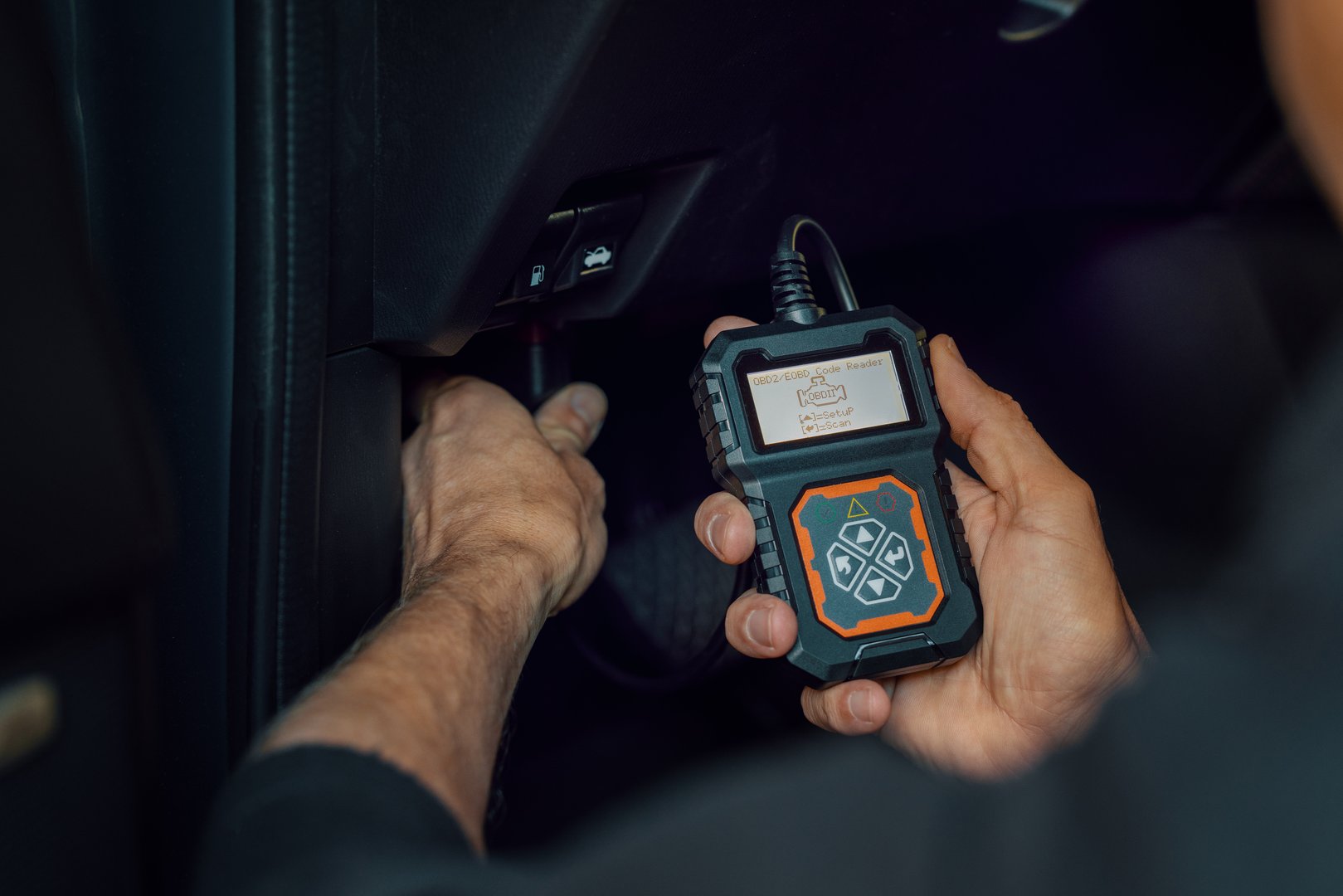 car mechanic using OBD2 scanner, code reader tool to check engine errors and for diagnostics