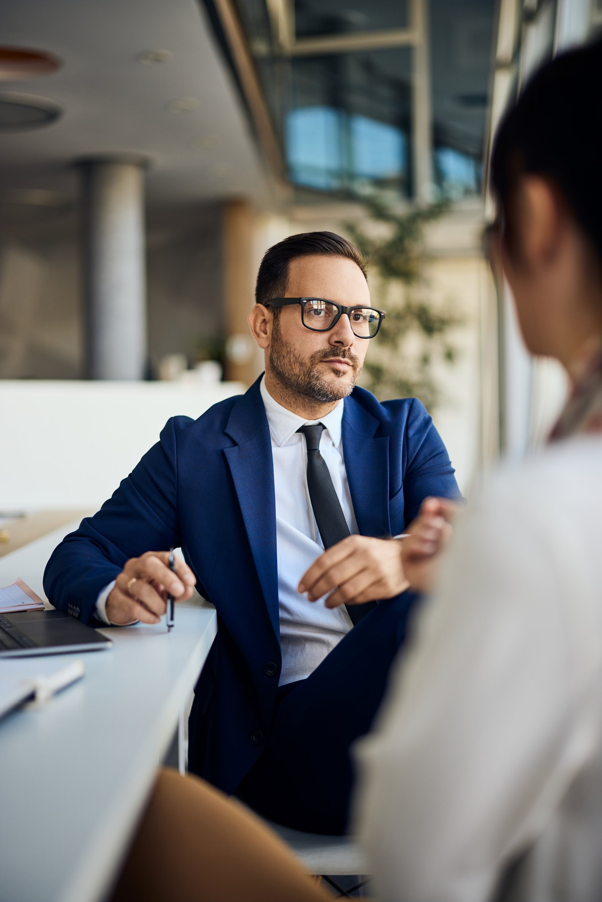 Two professionals engage in a serious business conversation at a contemporary workplace.