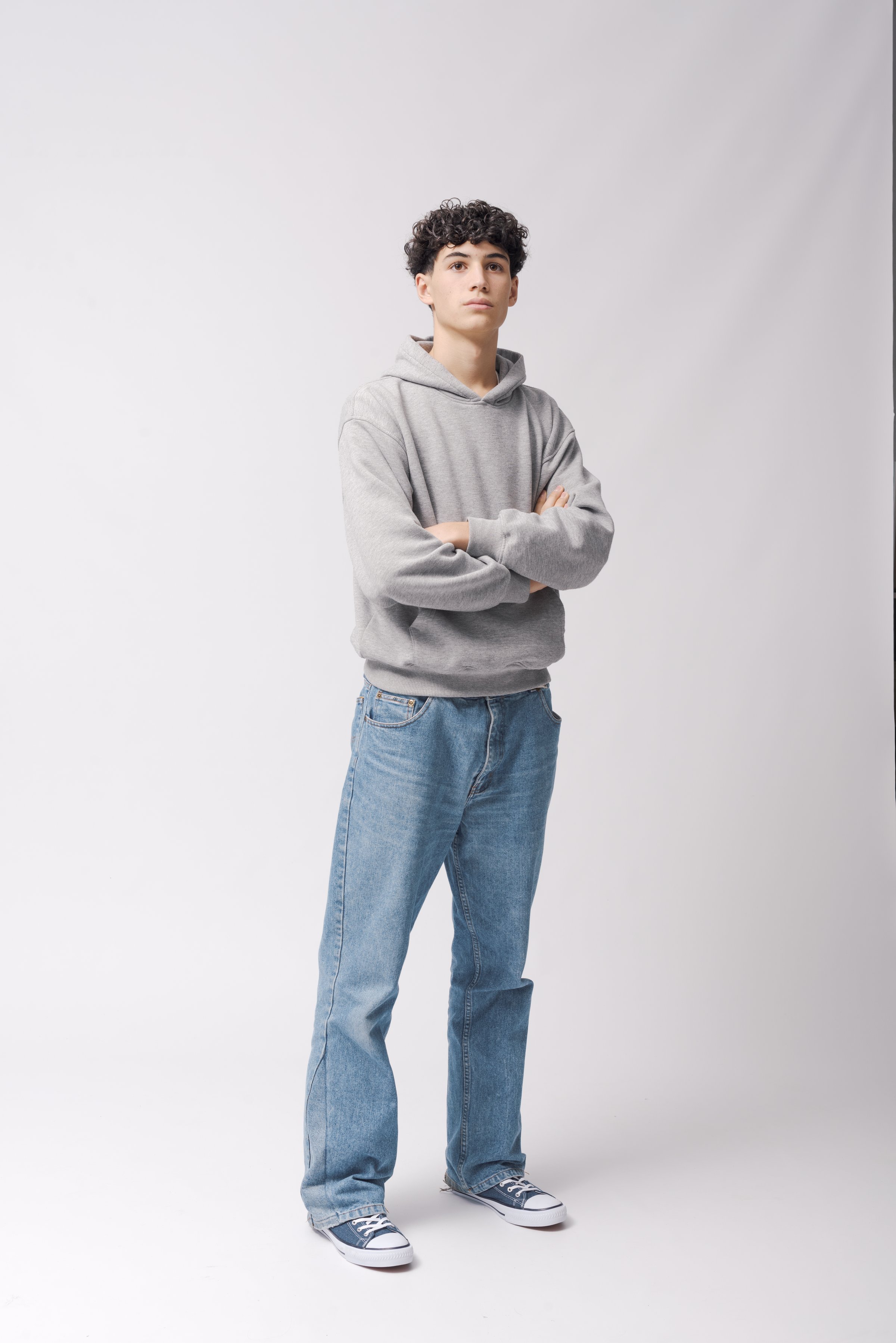 Portrait of a young cool guy standing and posing with arms crossed, full length, isolated on white background
