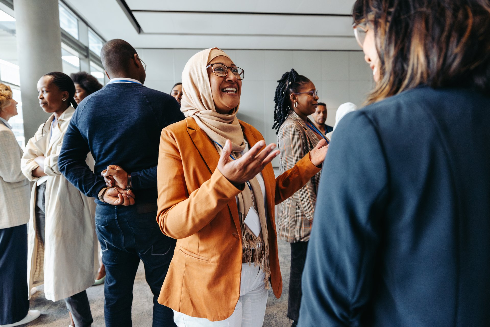 Smiling Muslim businesswoman sharing and talking with colleagues at a networking event. Professional women engaging in a lively conversation.
