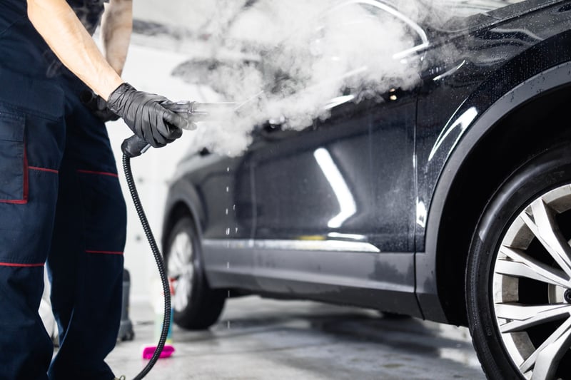 Cleaning expert using steam cleaner machine to clean the car.