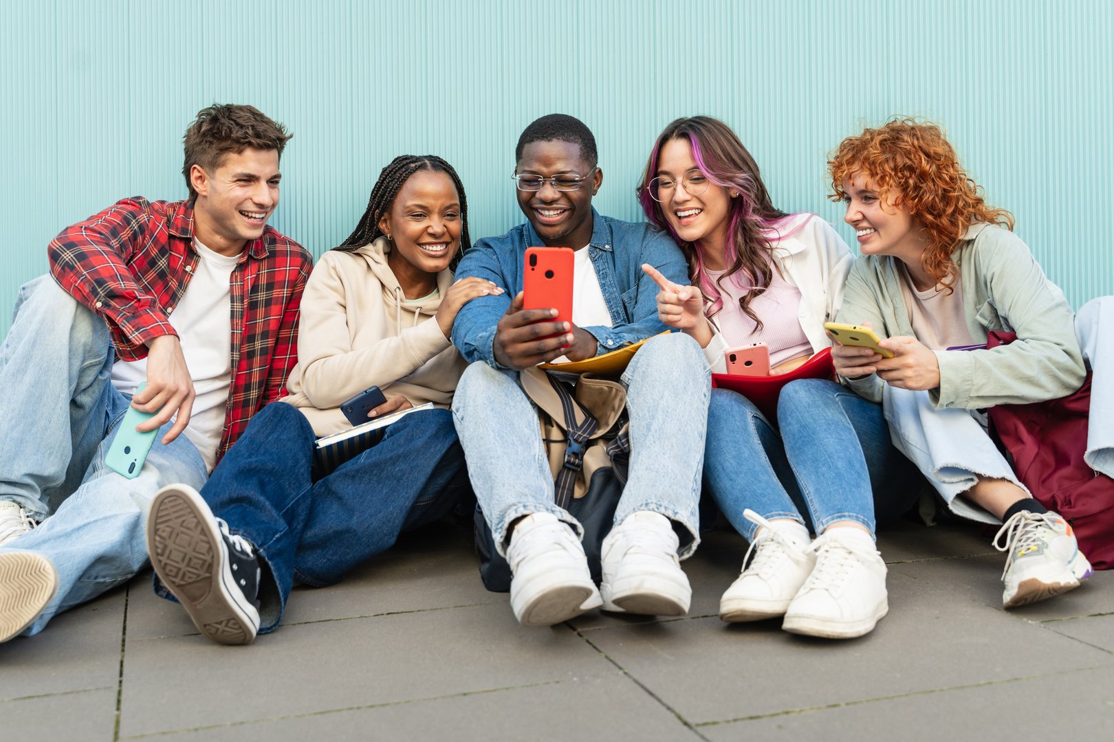 Student friends sitting on campus using mobile phone app to share content on social media