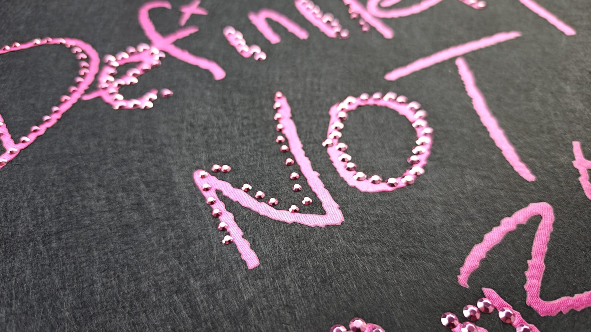 The word NOT written in pink paint with decorative dots on a black background, part of a larger handwritten text.