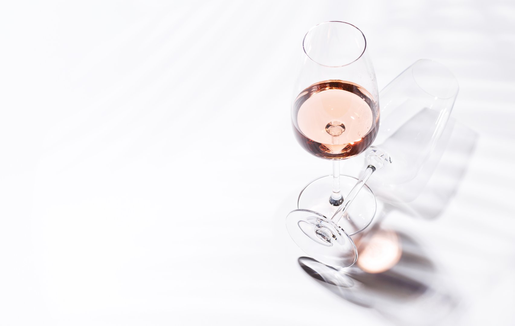 A glass of rose wine filled with the blush-pink beverage, set against a bright and elegant background. Perfect for celebrations or relaxed moments