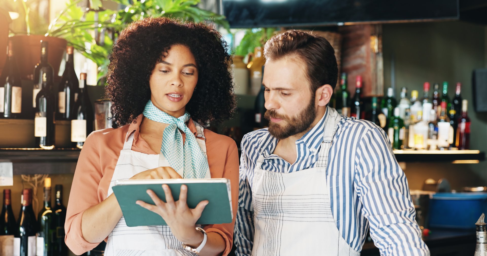 Planning, entrepreneur and team with tablet, cafe and review of order for inventory, people or discussion. Small business, woman and man with tech for sales, serious or colleagues with app in startup