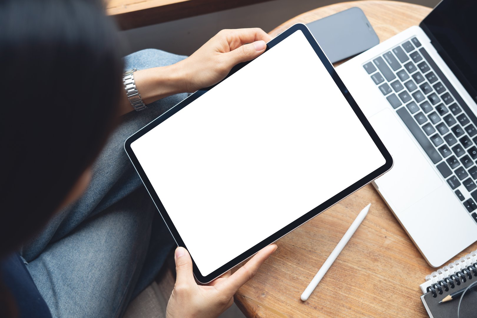 Mockup balnk screen digital tablet. Woman holding digital tablet with blank white screen with laptop computer on table at coffee shop, template for web app design or social media marketing