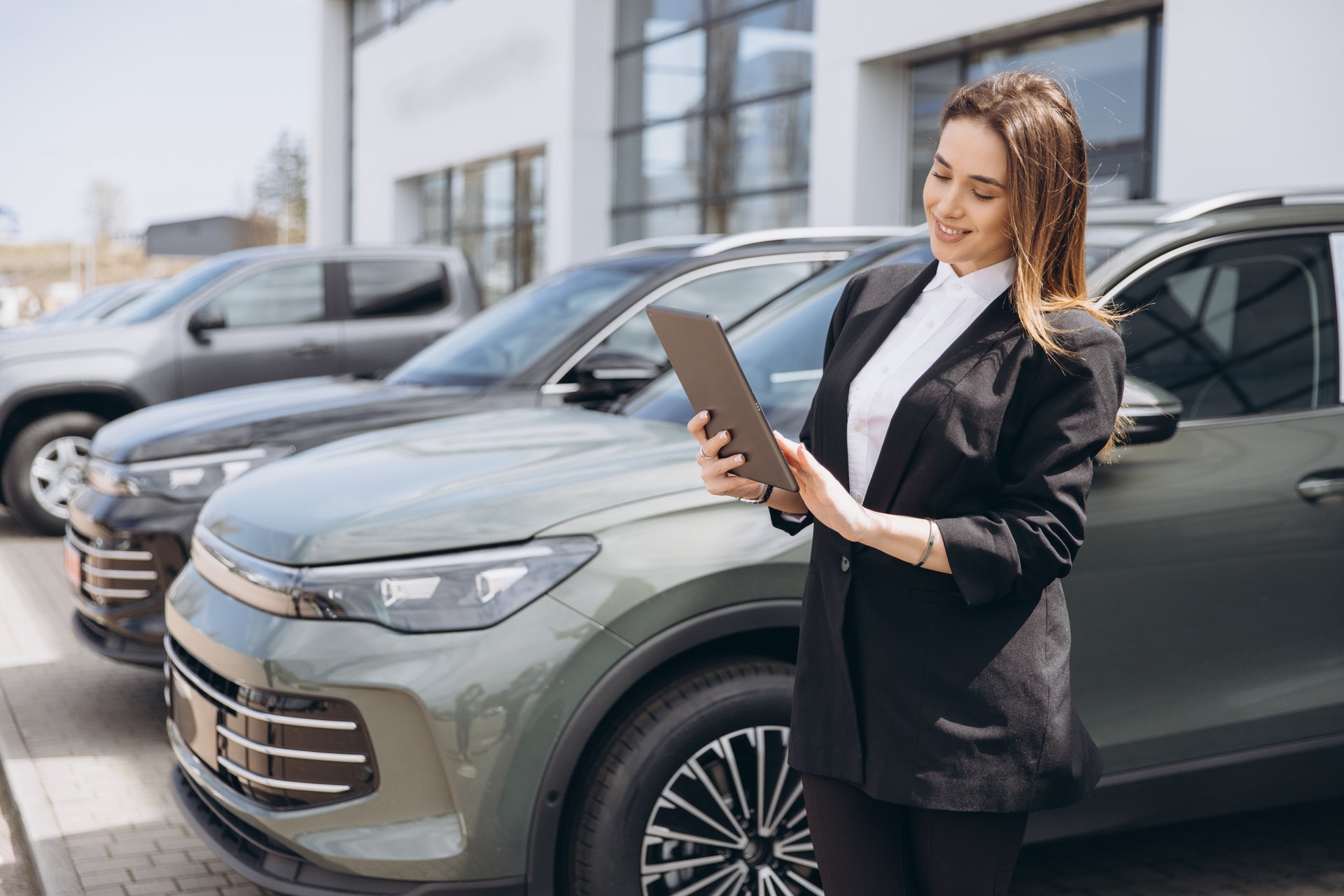 Saleswoman using digital tablet while working at car dealership