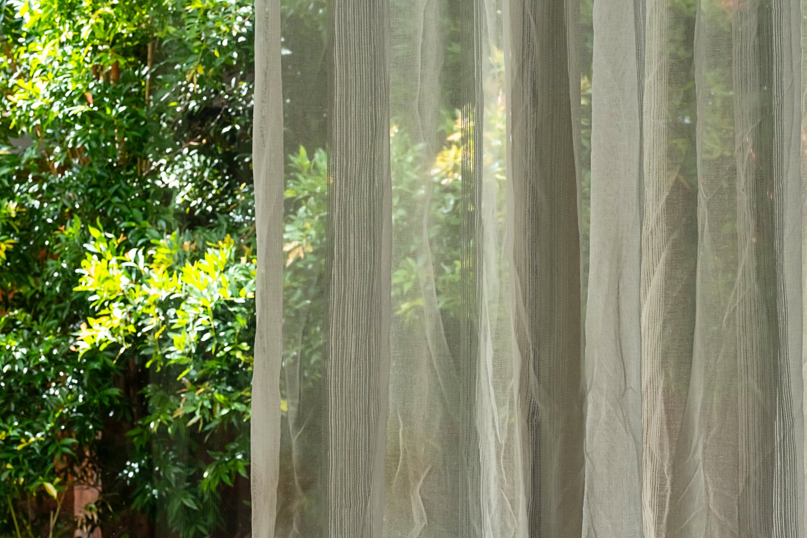 Sheer curtains with green trees visible through them.