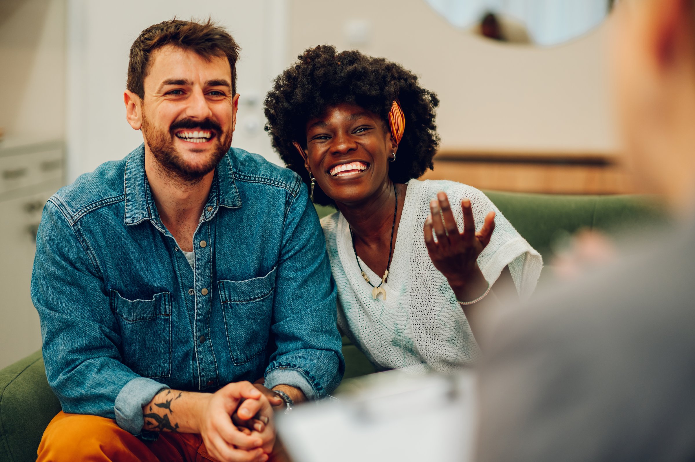 Young multiracial couple smiling because solved conflict at couple therapy session with a counseling adviser and. Diverse spouses being happy with a psychologist advises. Copy space.