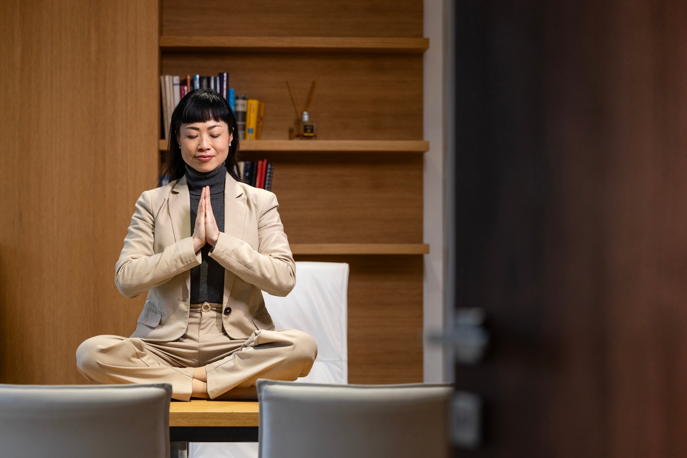 Businesswoman taking a break on her job and relaxing while doing yoga exercises in her office.