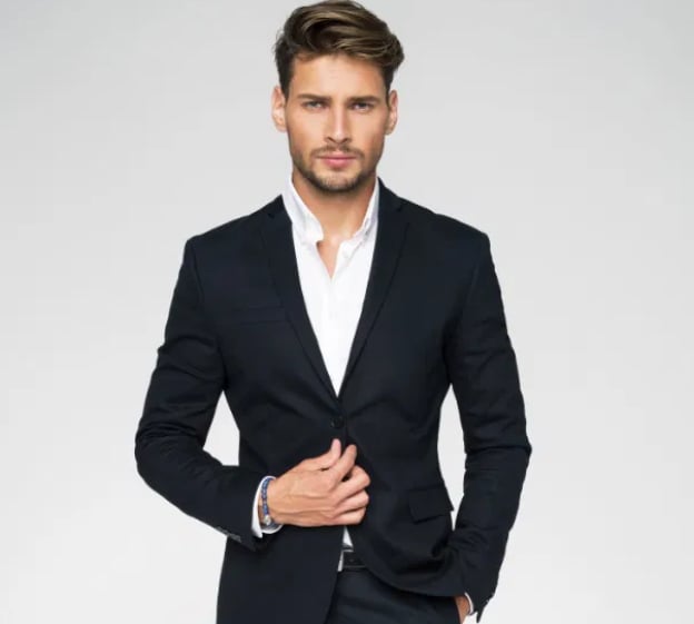 Man in a dark suit and white shirt posing against a plain background.