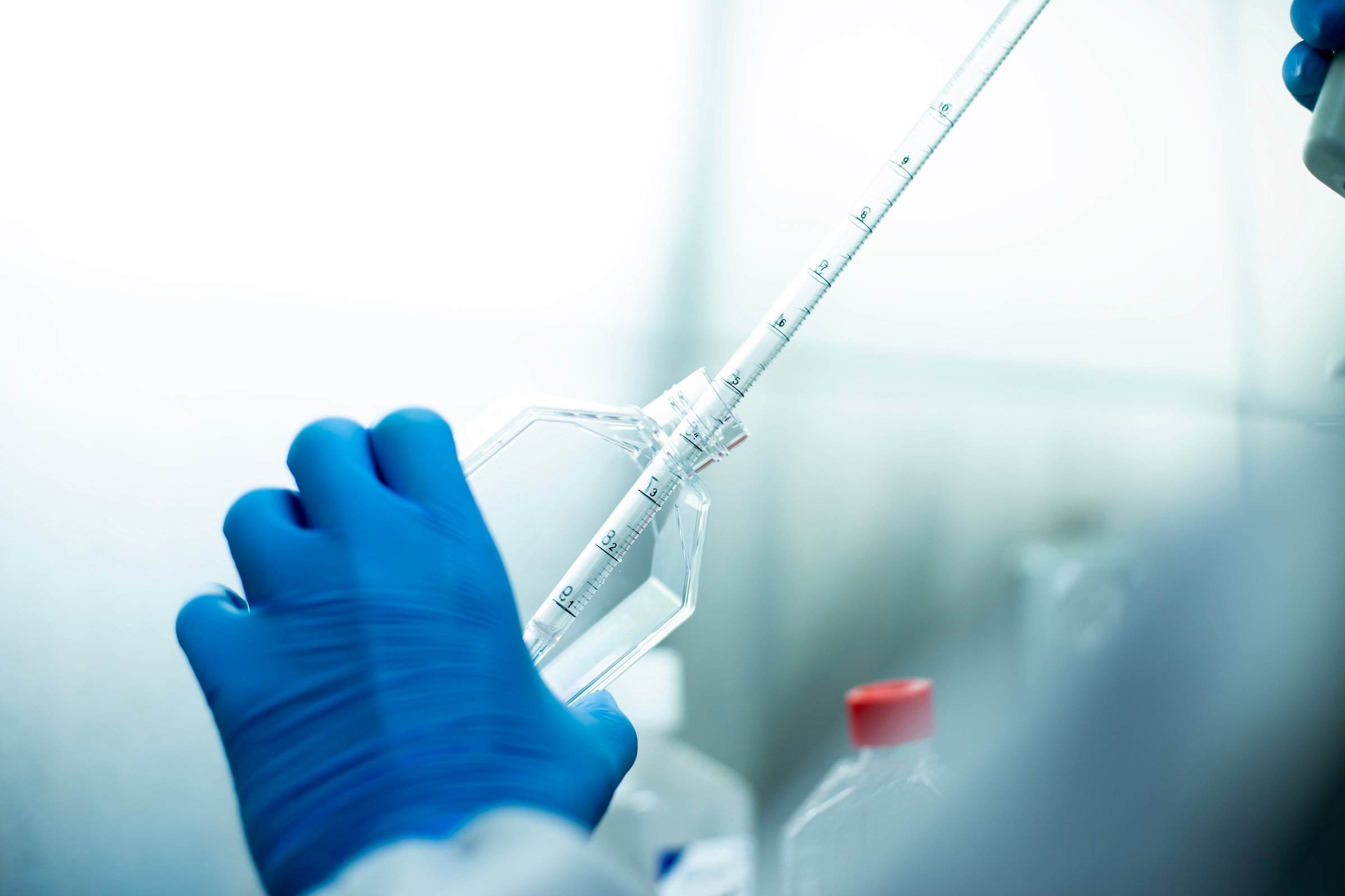 A chemist wearing protective gloves conducting a scientific experiment in a laboratory