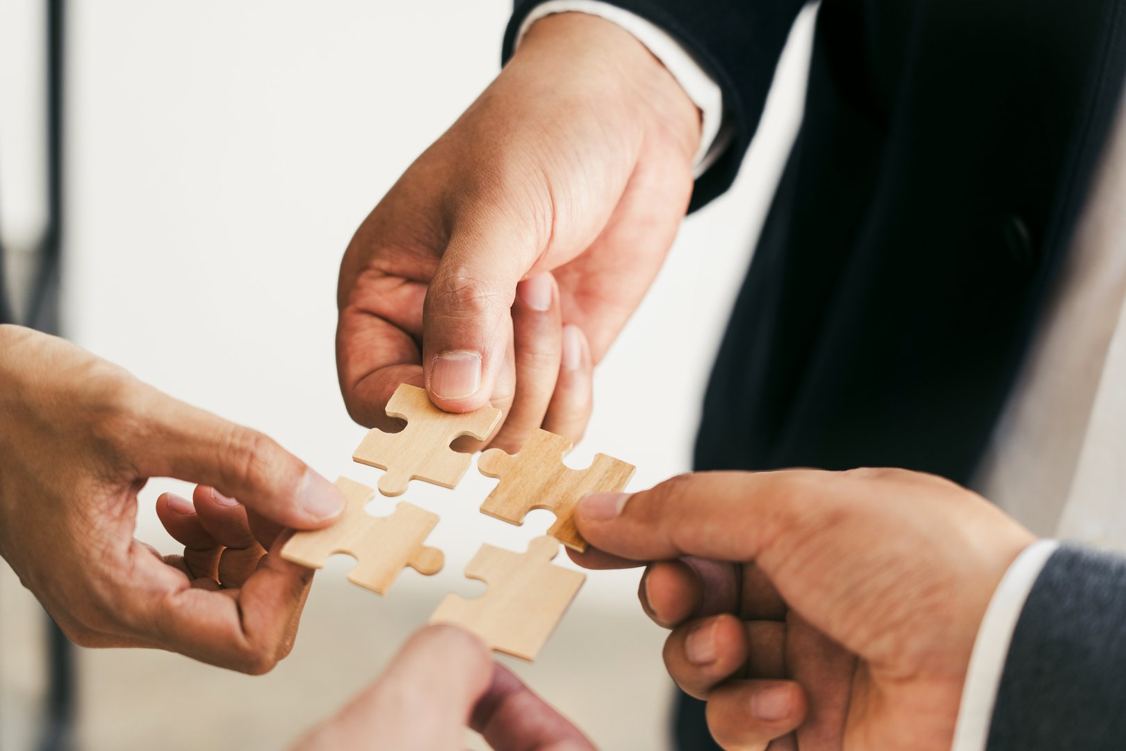 The concept of teamwork and partnership. Businessman's hands putting together puzzle pieces in the office and join together in a jigsaw puzzle team. Charity. Volunteers. Business unity as a team.