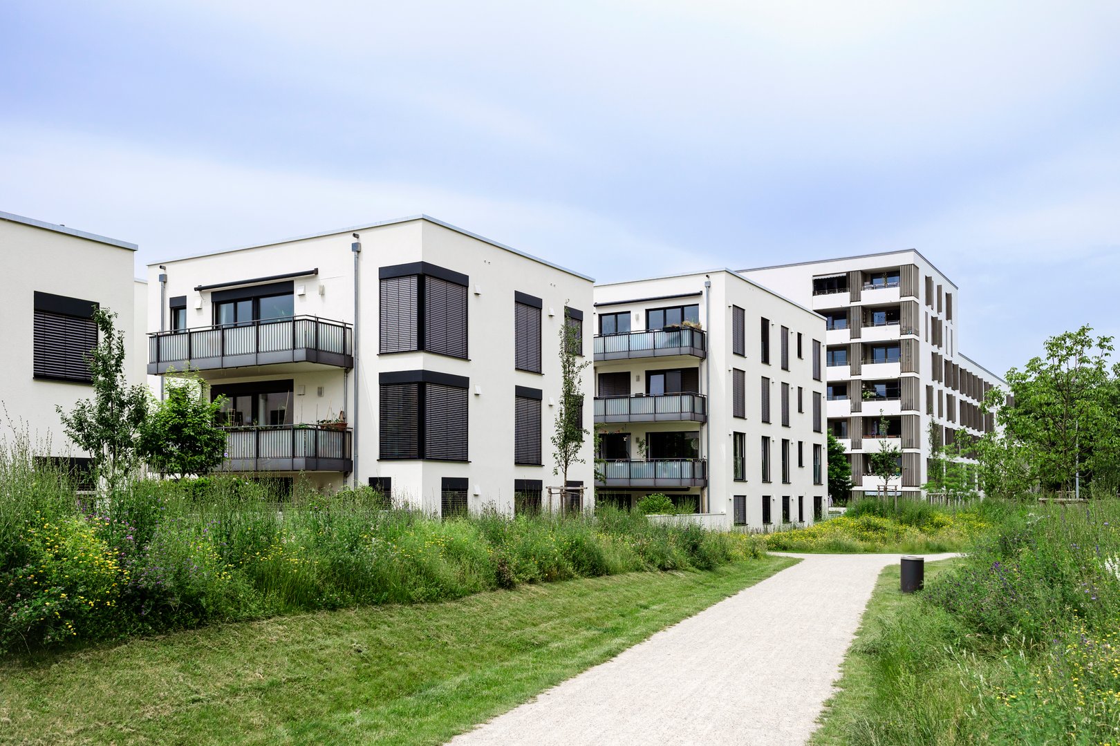 Residential Modern Buildings in Germany Munich with White Facade, Green Landscaping. Comfort Multifamily Low rise, High rise Block of Flats or Apartment Building. New Living Building Complex.