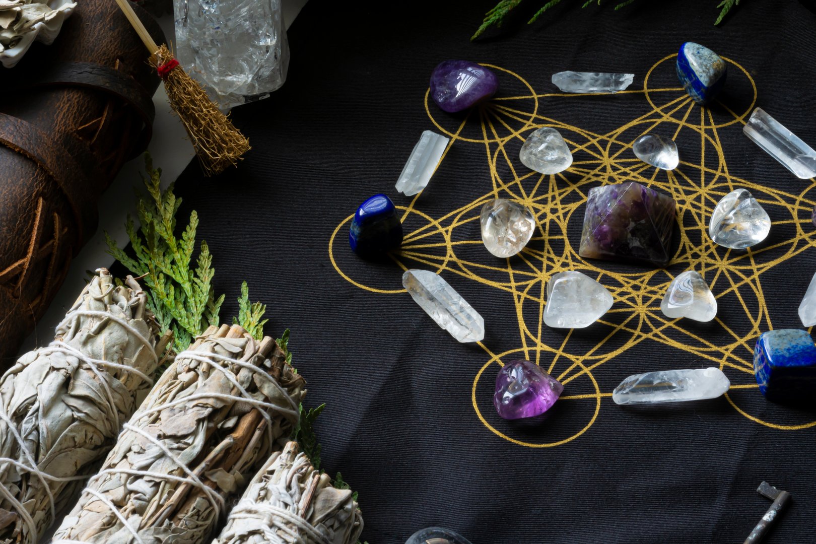 A top view image of a crystal grid made up of amethyst and clear quartz crystals and white sage smudge sticks.