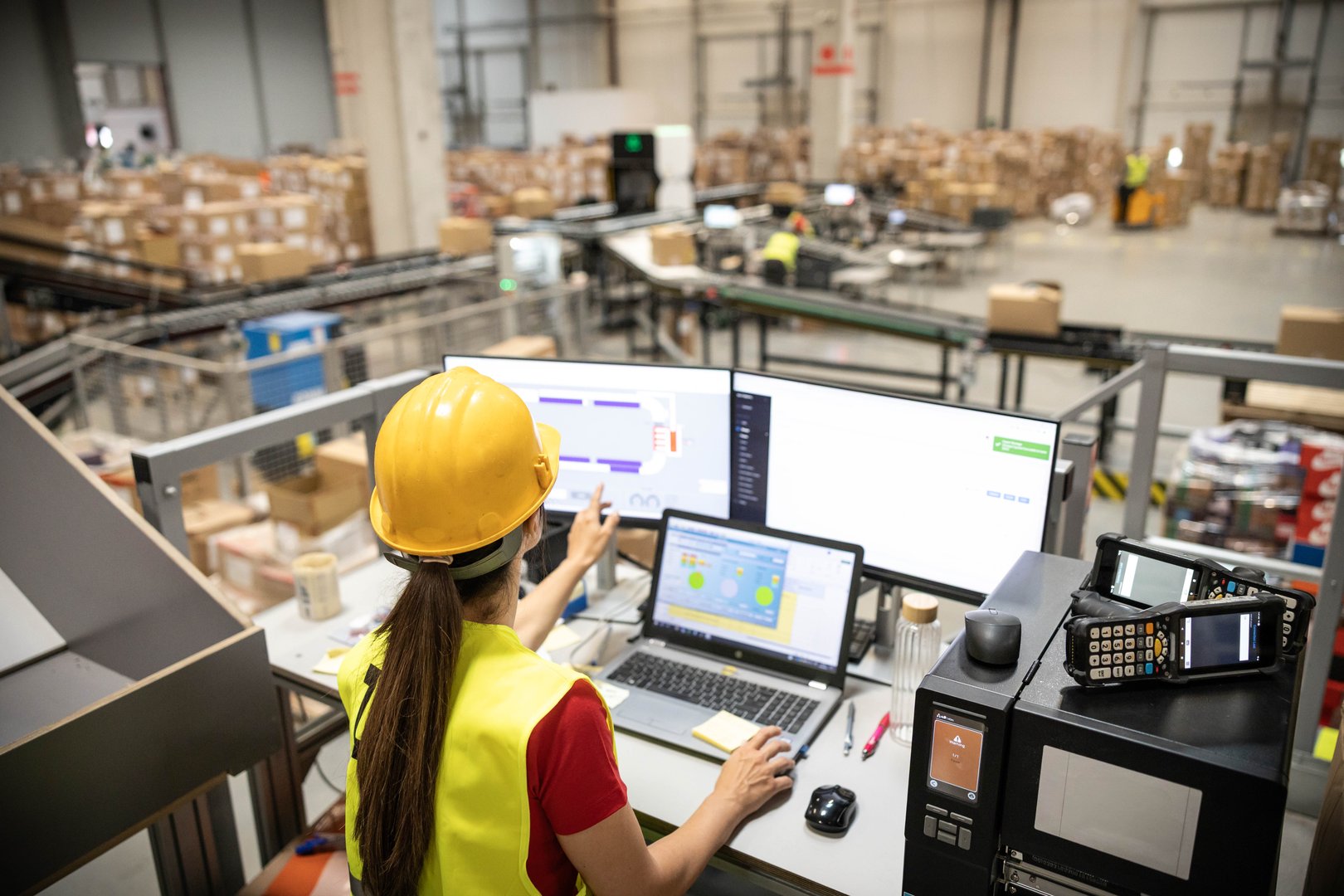 A woman is analyzing real-time data on her computer within a warehouse, demonstrating tech integration in logistics.