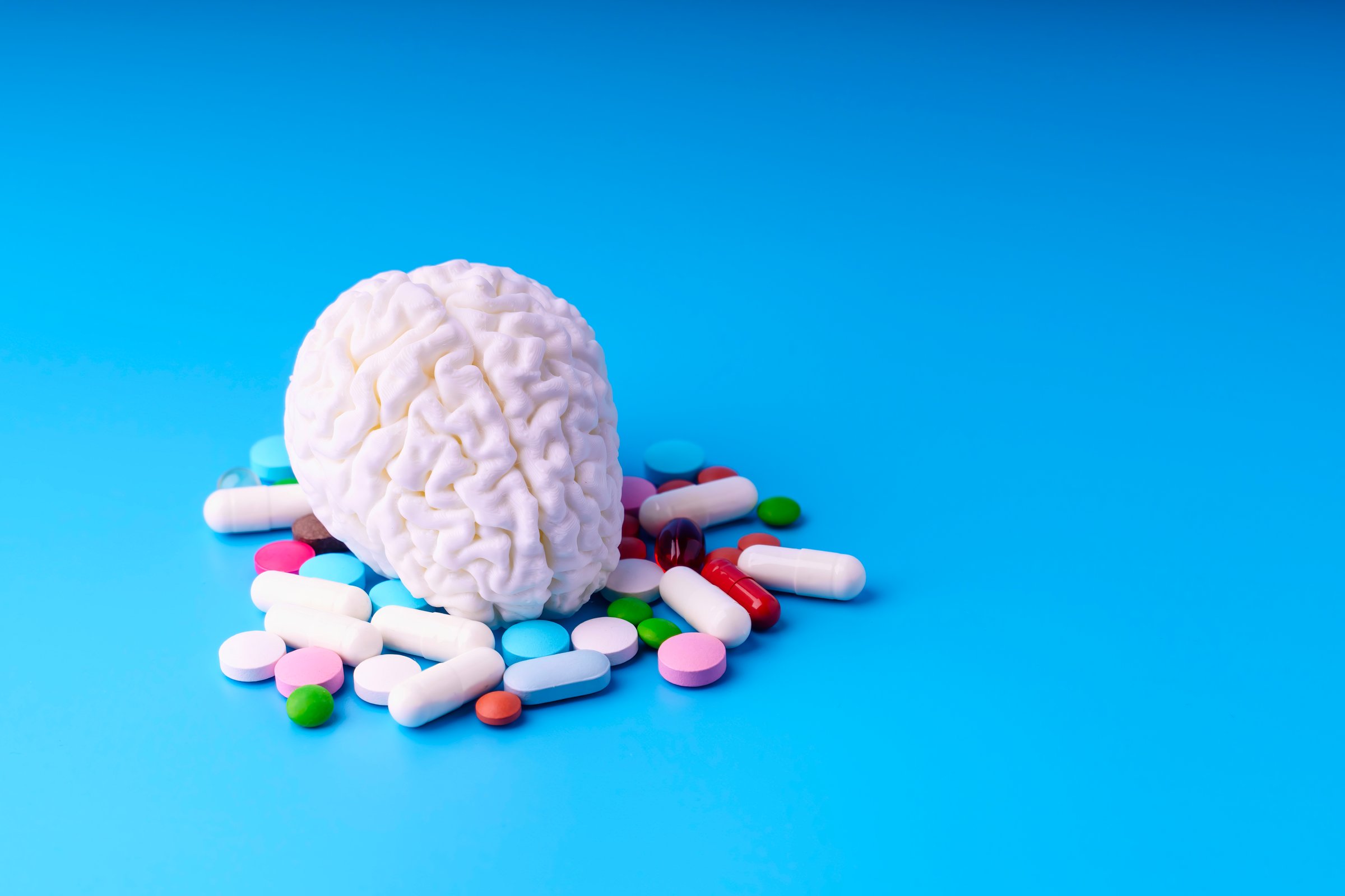 Brain on blue background surrounded by various pills