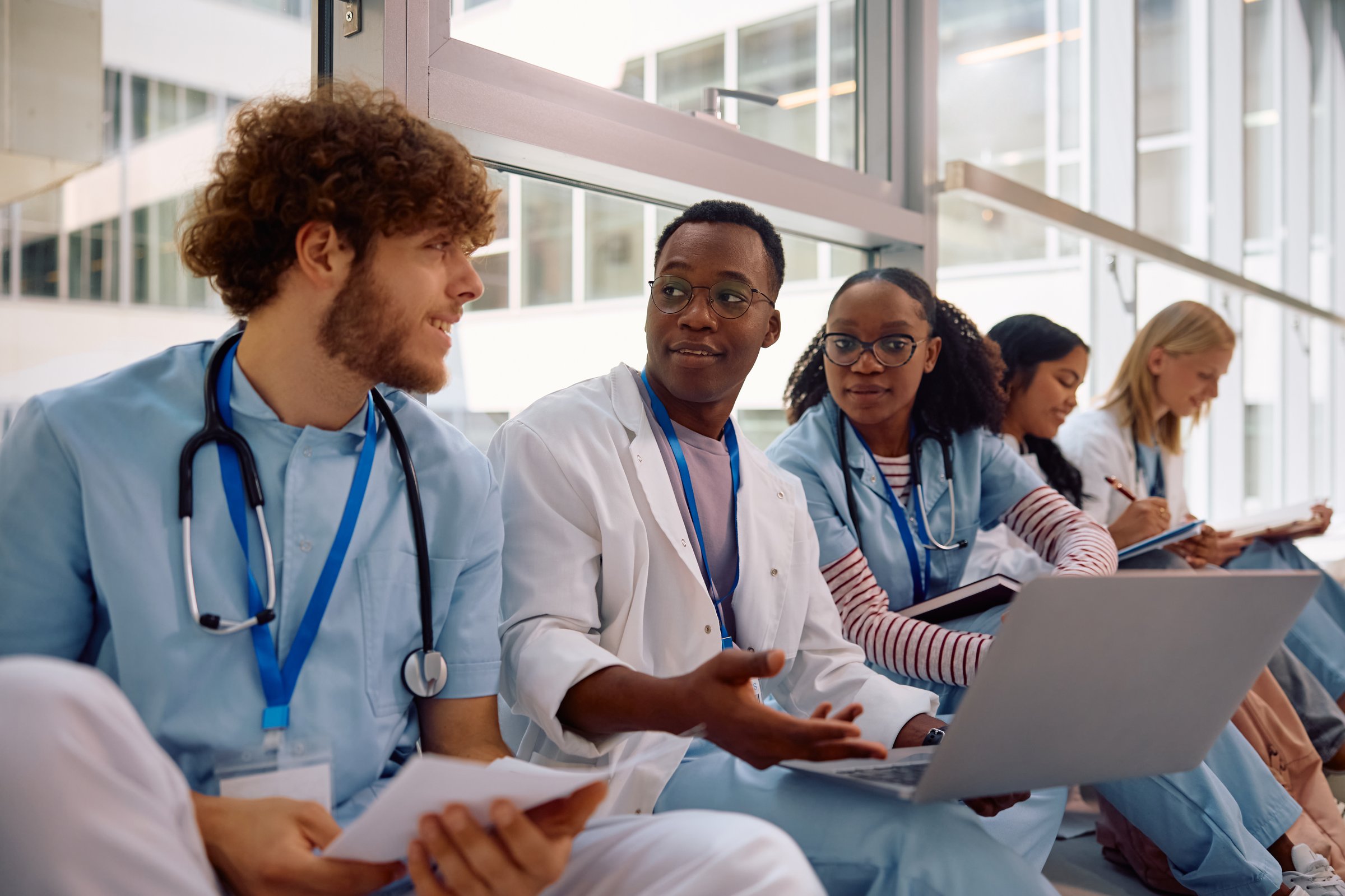 Multiracial group of medical students using laptop in university hallway. Focus is on African American student.