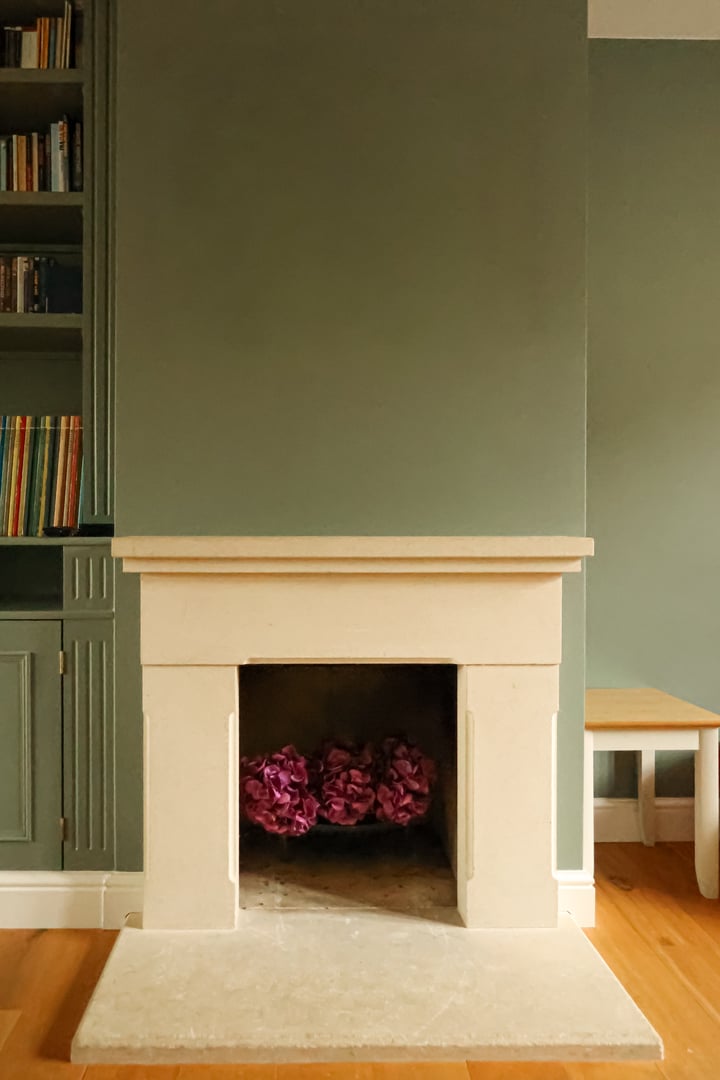 Elegant fireplace and mantelpiece in a modern minimalist living room. Decorating an interior space with natural stone, wood, and floral accents