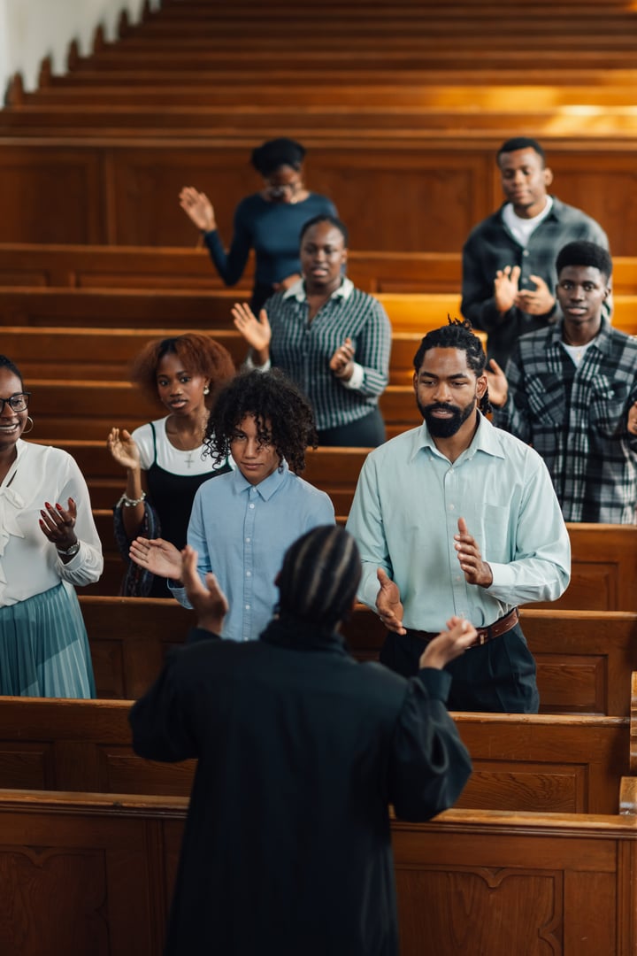 Diverse churchgoers clap and sing in pews during uplifting sunday service