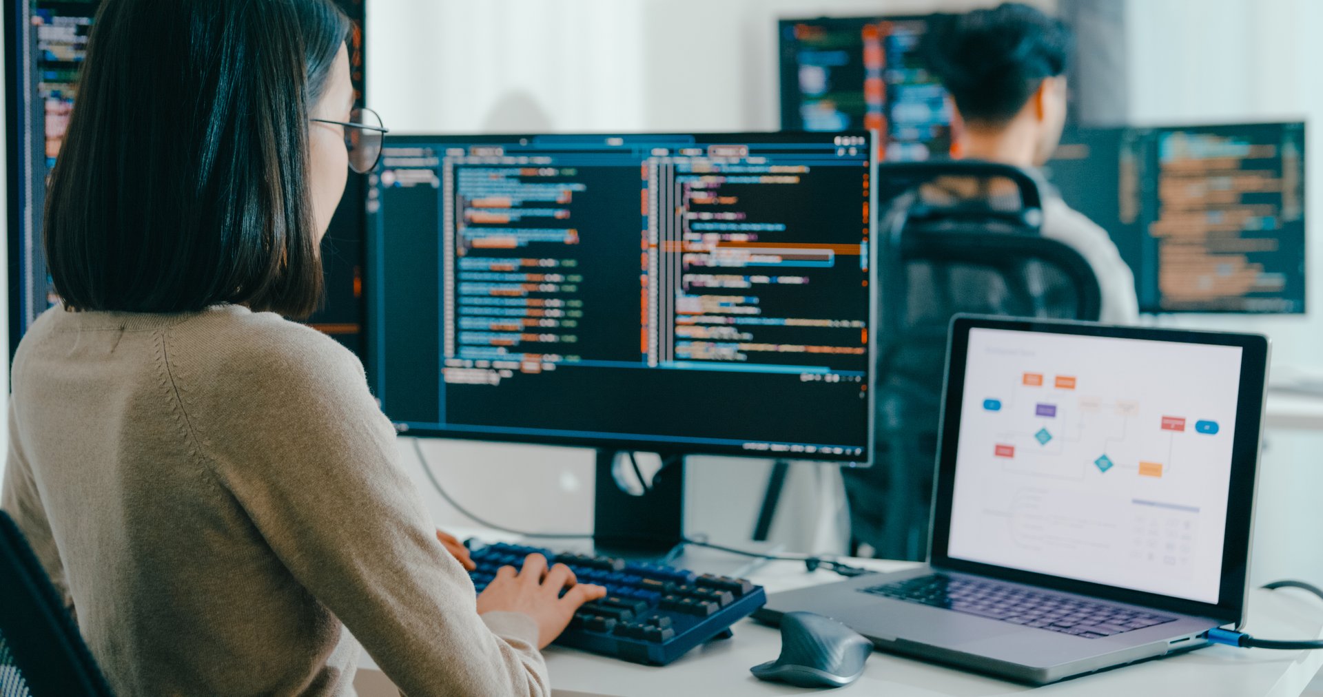 Desktop application development showing programmers working on software interfaces with multiple monitors