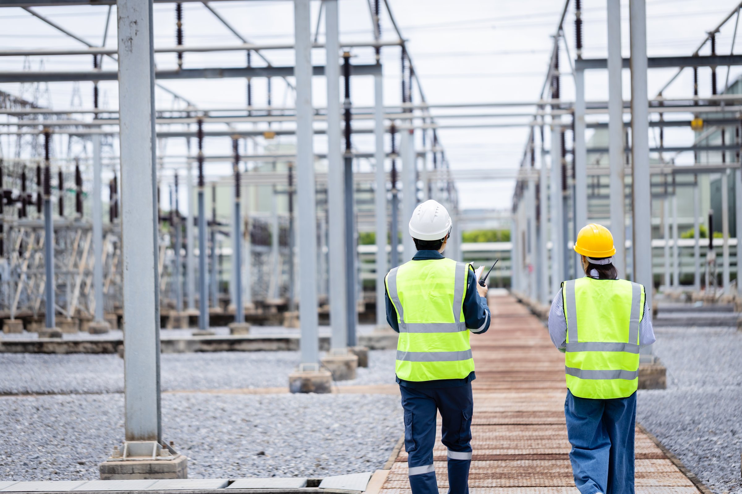 An engineer is working at high voltage power substation performing inspection and check of infrastructure to ensure safety and proper operation of electrical system