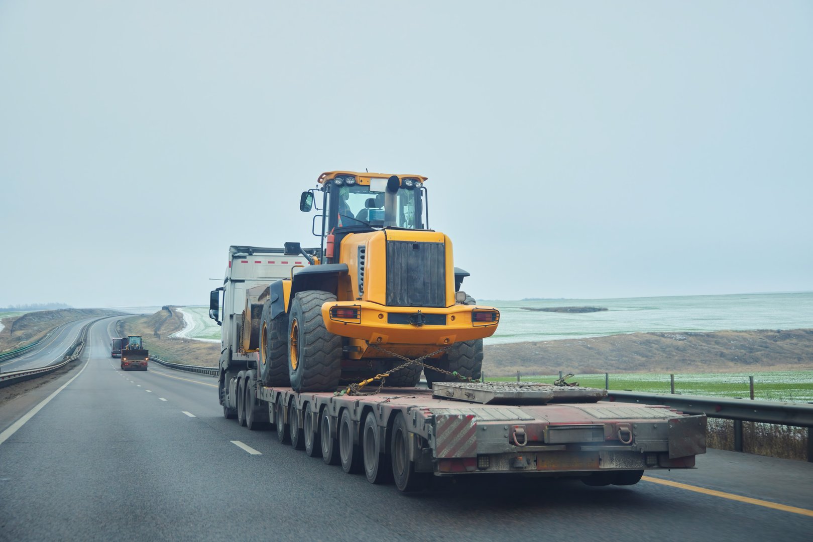 Tow truck carries a broken tractor along the highway