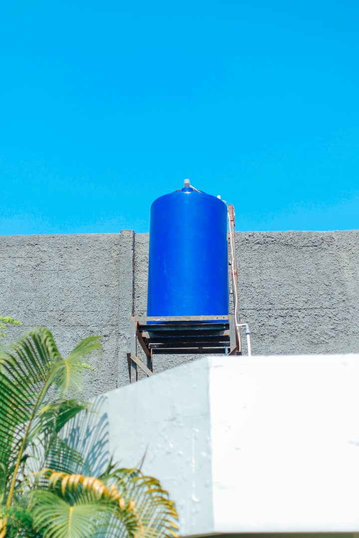Blue water tank installed on top of a building, in a concrete structure. Reservoir used for storing water.
