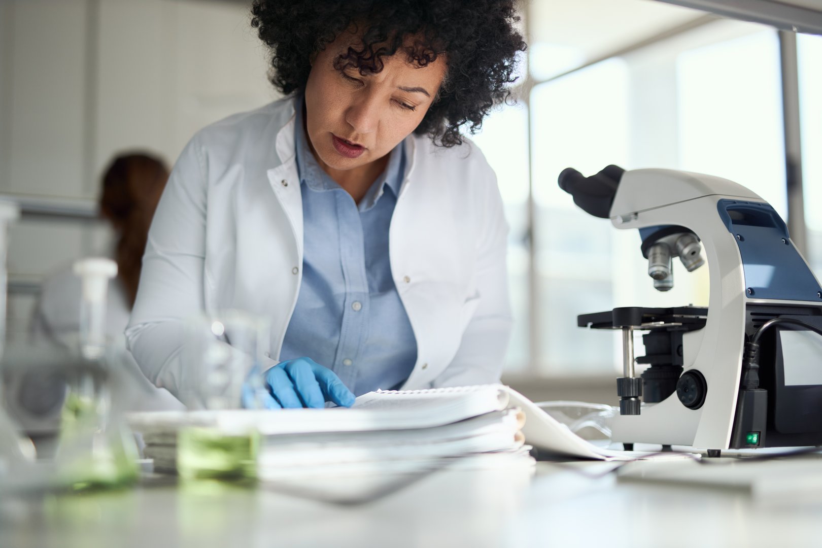 Female chemist doing some research while reading scientific books in laboratory