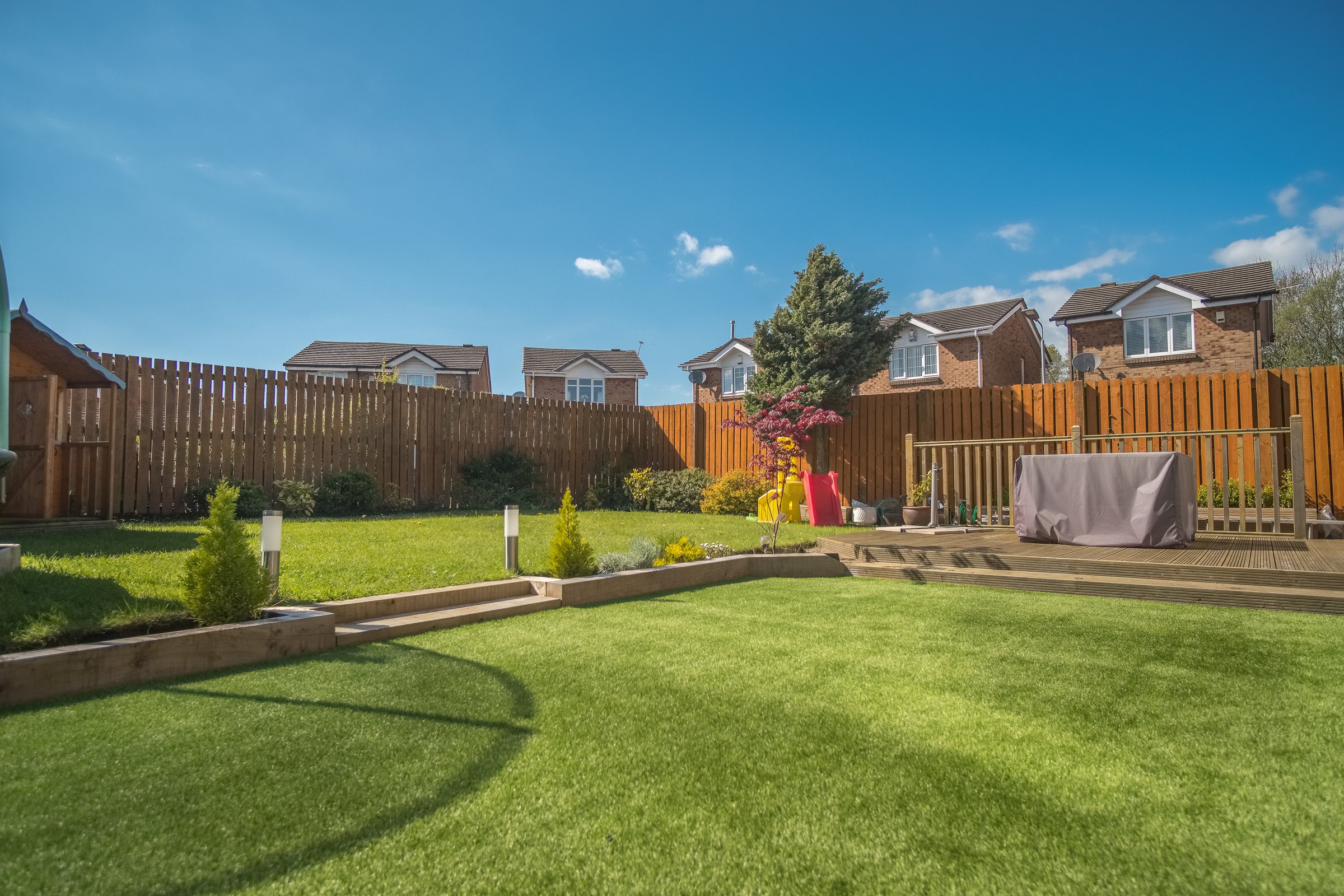 A newly completed and replanted landscaped garden with mixer of artificial and natural sown grass, new borders planted, a new decking patio and garden ornaments surrounded by new erected wooden fencing all to a modern design