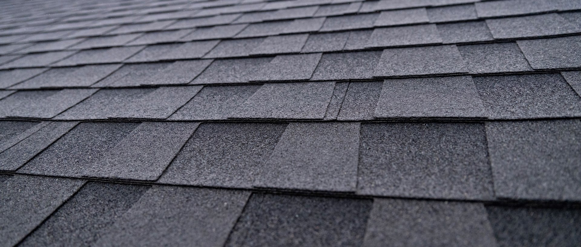 Selective focus texture of dark gray asphalt roof shingles