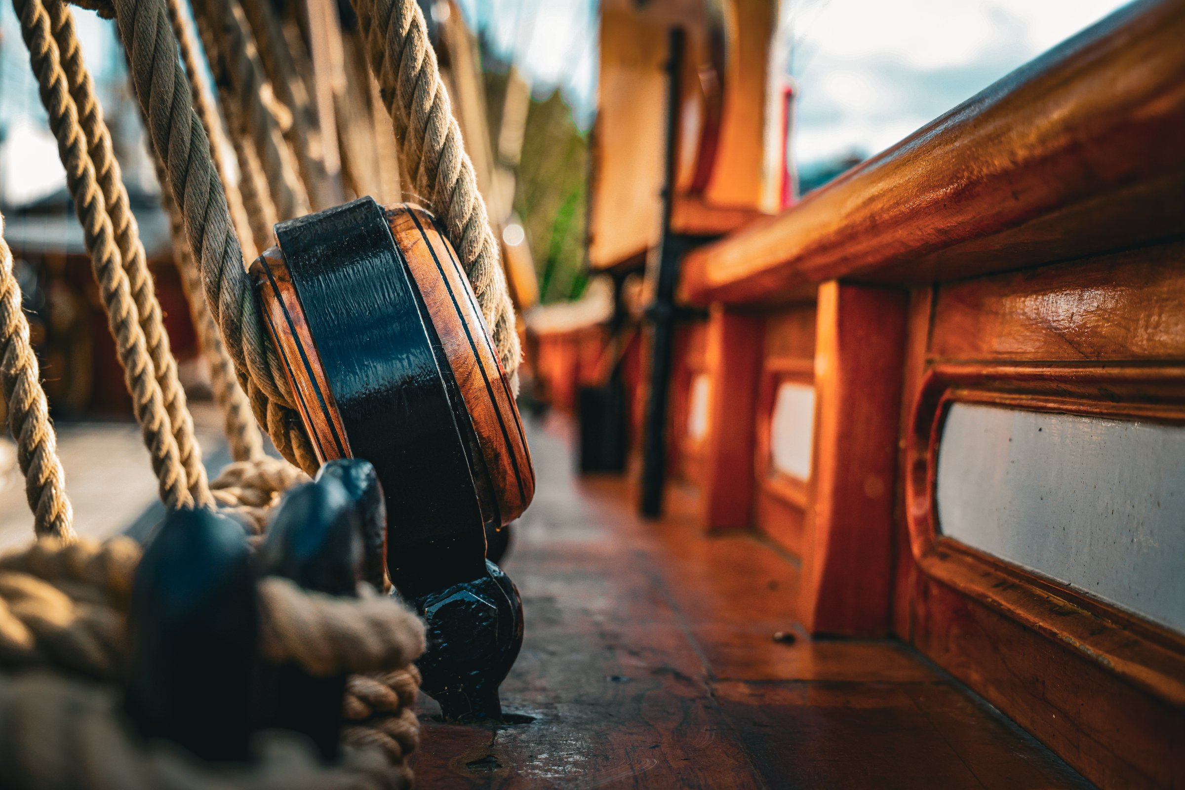 A close-up view of rigging and wooden details aboard a classic sailing ship, showcasing the craftsmanship, ropes, and maritime textures that define traditional seafaring vessels.