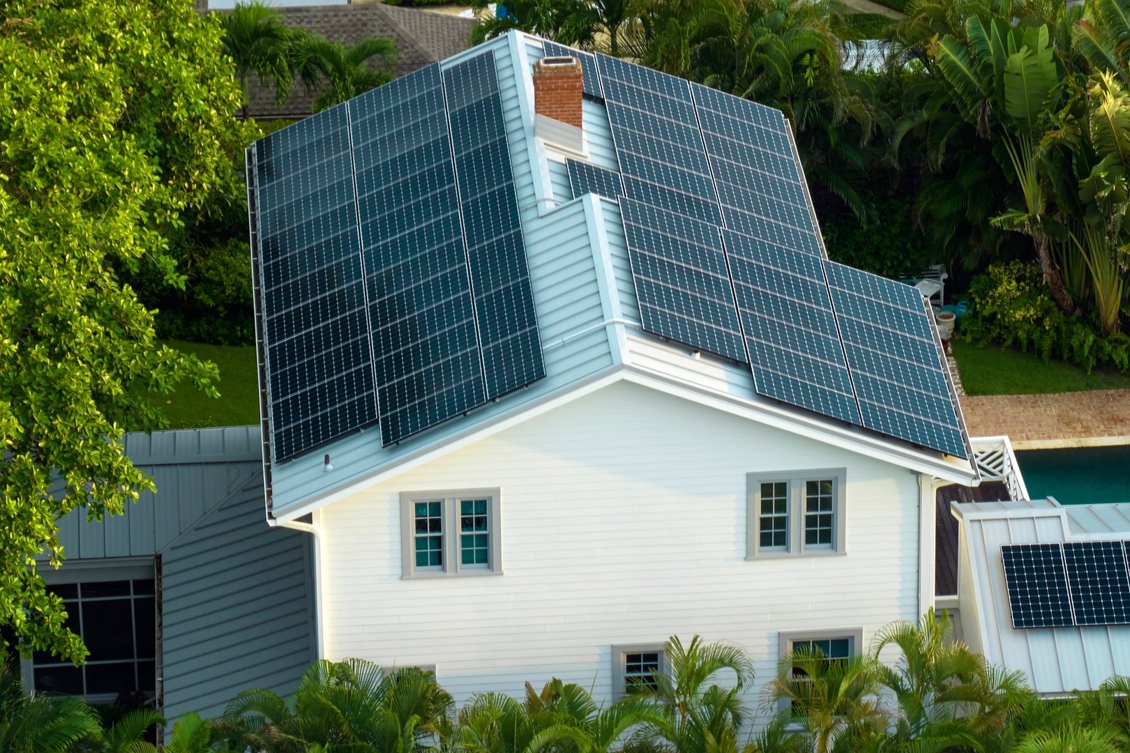 New residential house in USA with roof covered with solar panels for producing of clean ecological electricity in suburban rural area. Concept of investing in autonomous home for energy saving.