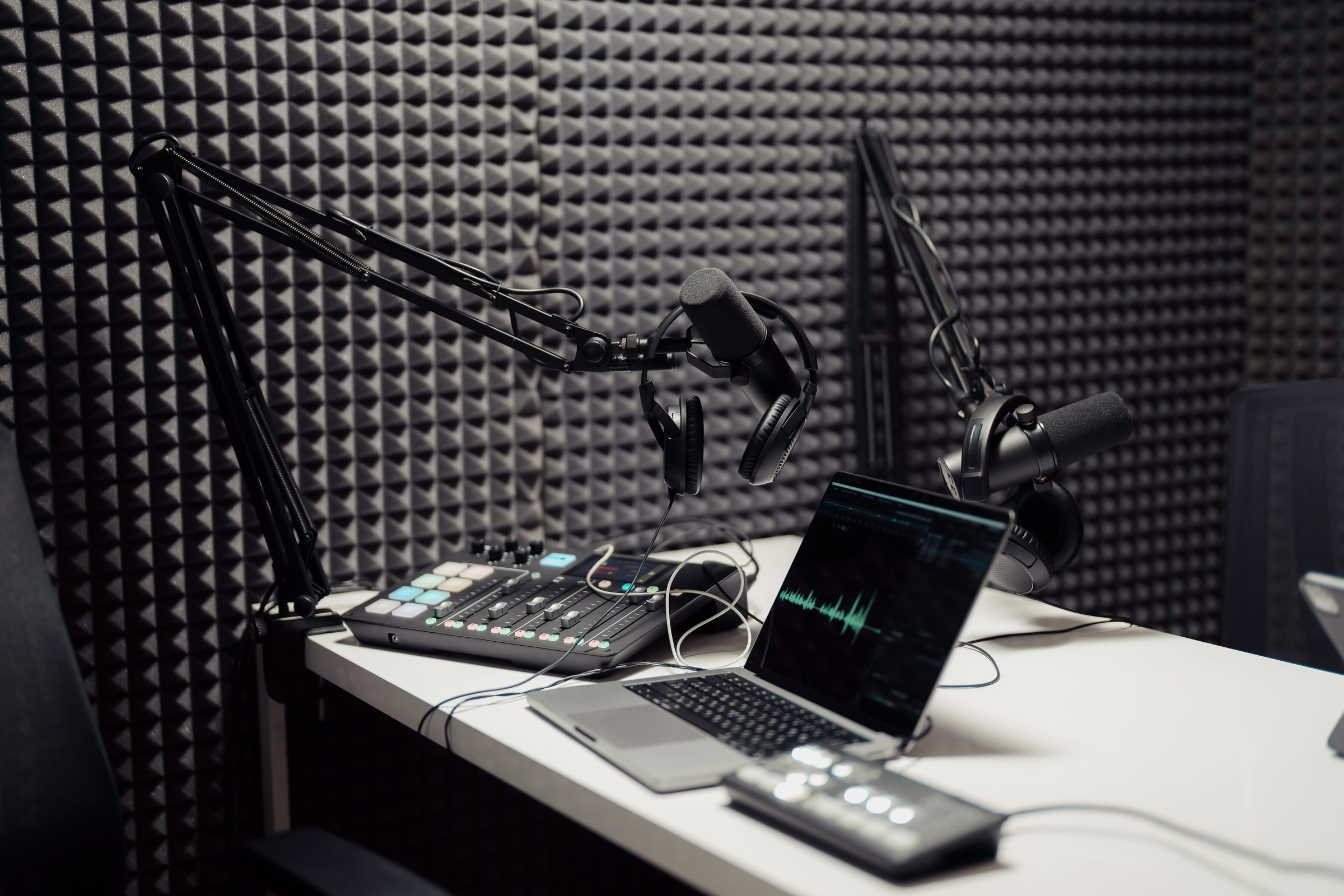 Modern laptop connected to mixing consoles and microphones during podcast in modern recording studio