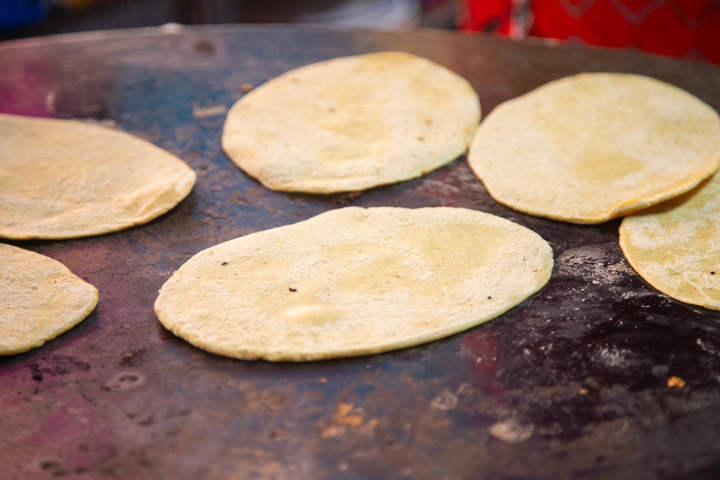 Cooking memelas in Oaxaca Central de Abastos Market with local cheese, pork jerky, eggs and hot sauce..