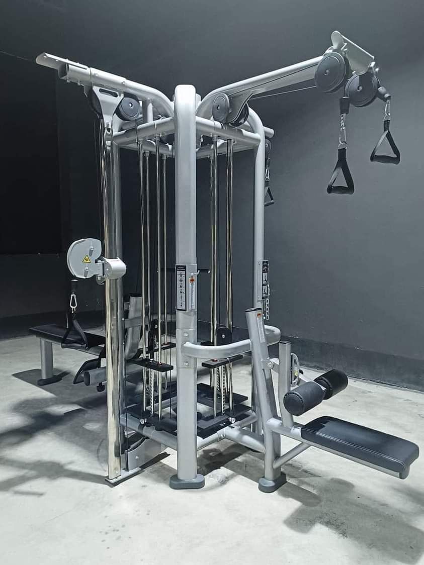 Multifunctional cable machine in a gym with pulleys and handles for strength training.