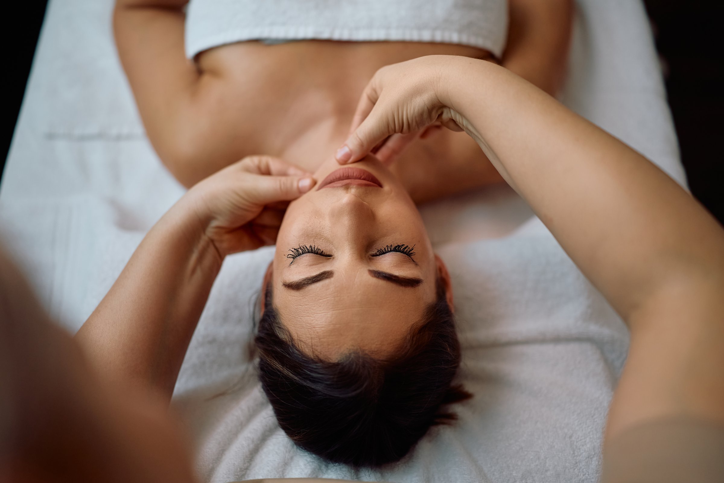 High angle view of a woman receiving facial massage at the spa.