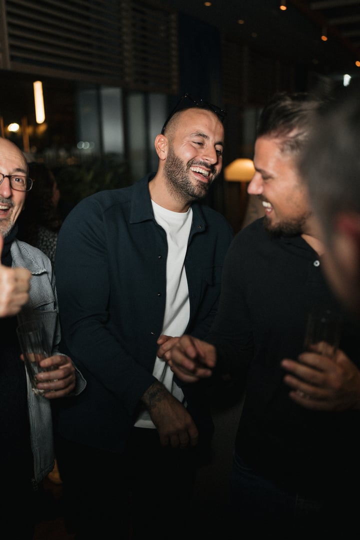 Business professionals gather after work for drinks and casual conversation. A relaxed office party moment showing teamwork, connection, and positive workplace culture in a corporate environment.